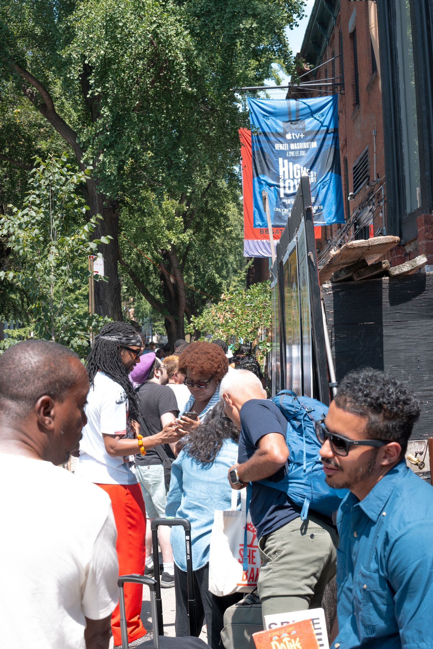A crowd of people waiting in line outside a building with blue banners hanging above.
