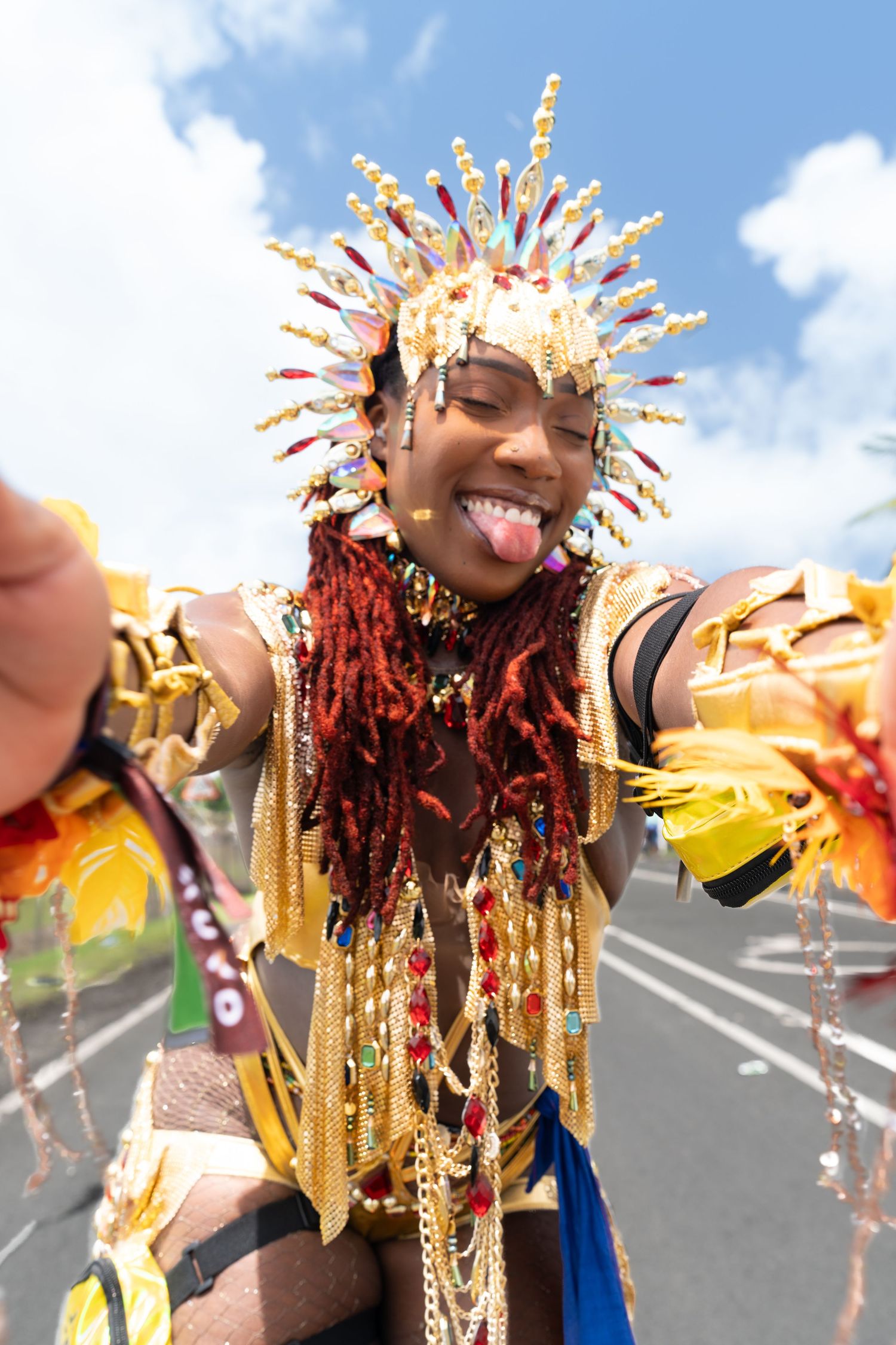 Festival performer wearing elaborate golden headdress with decorative elements at outdoor celebration.
