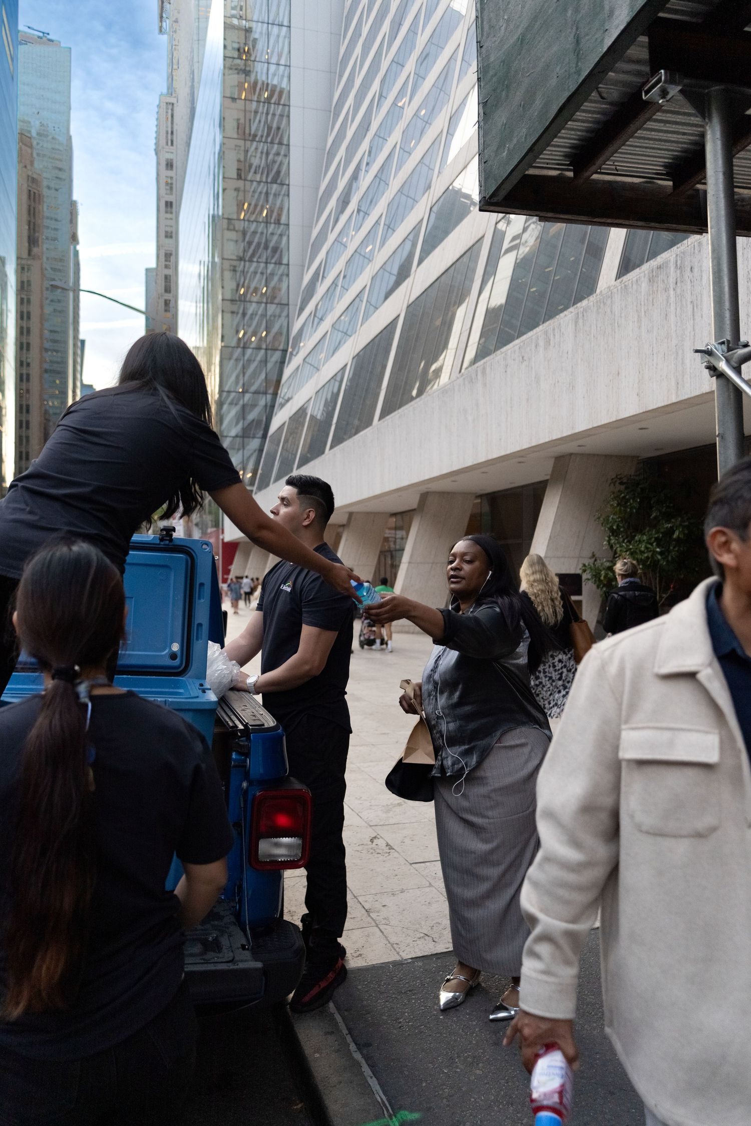 People interacting with a bright blue vehicle parked outside a modern building.