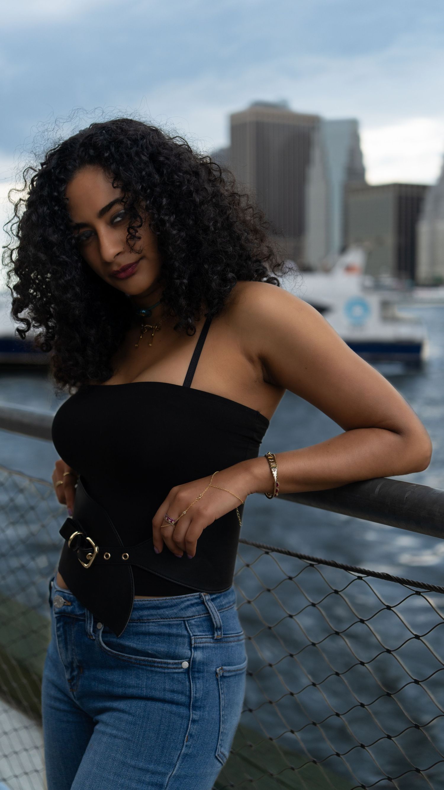 Stylish portrait poses against a waterfront setting with downtown buildings in view.