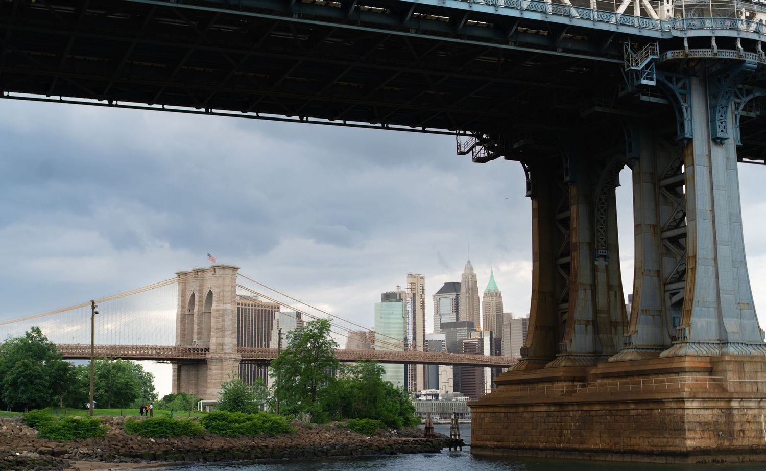Bridge supports and industrial buildings along a waterway at dusk.