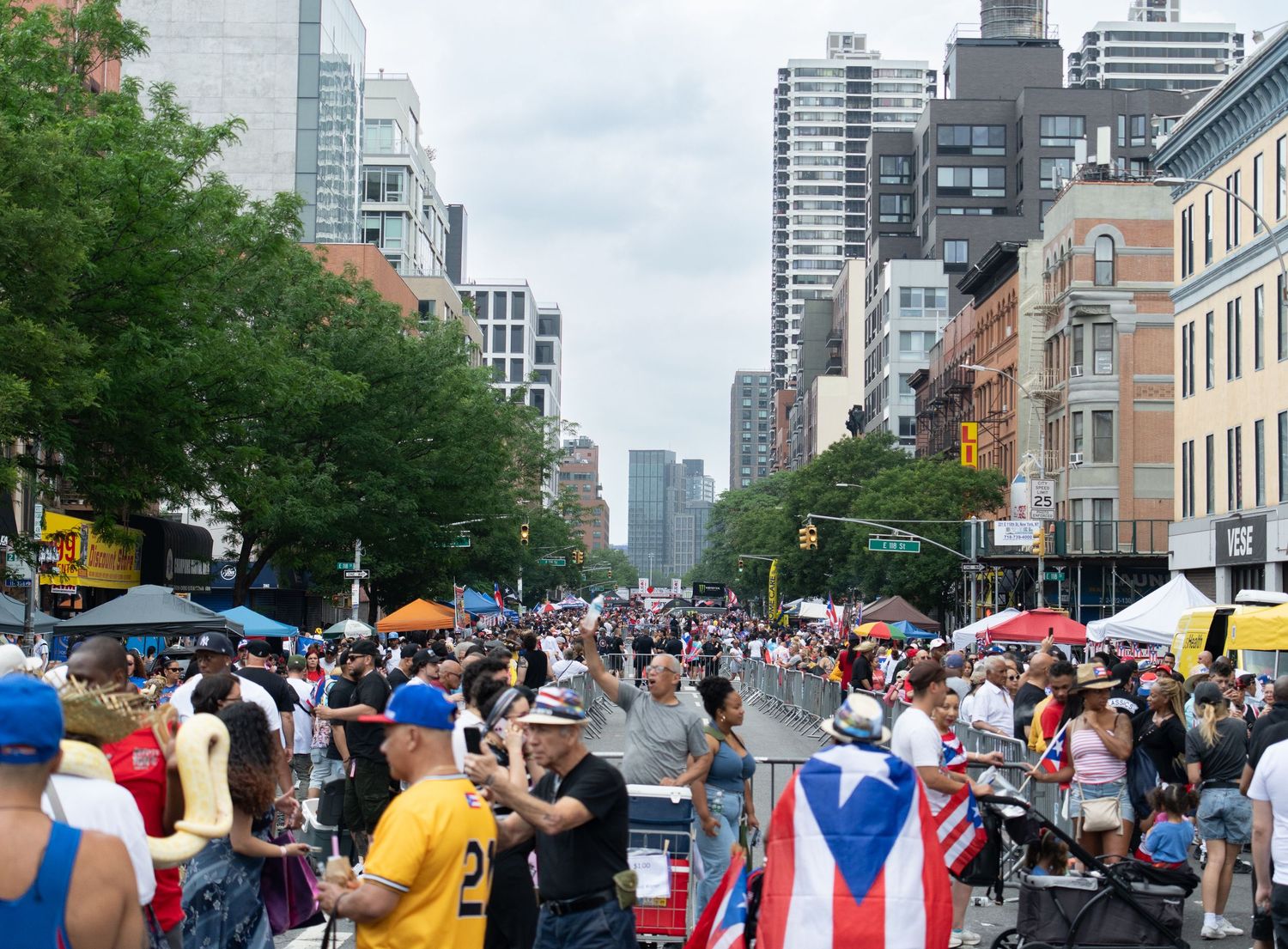 Panoramic view of a crowded urban street festival with tall buildings in the background.