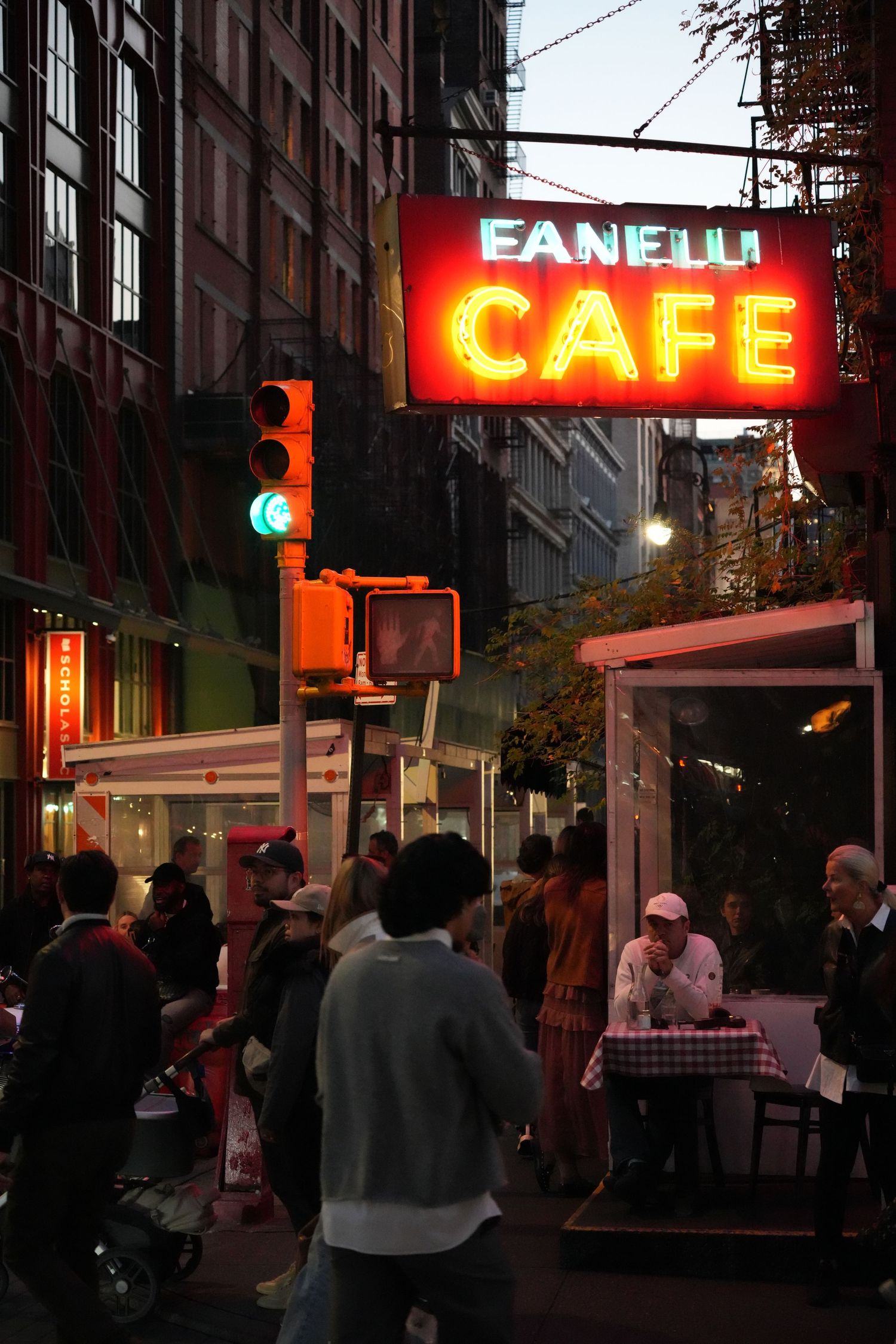 Illuminated neon cafe sign glows against dark urban streetscape at night.