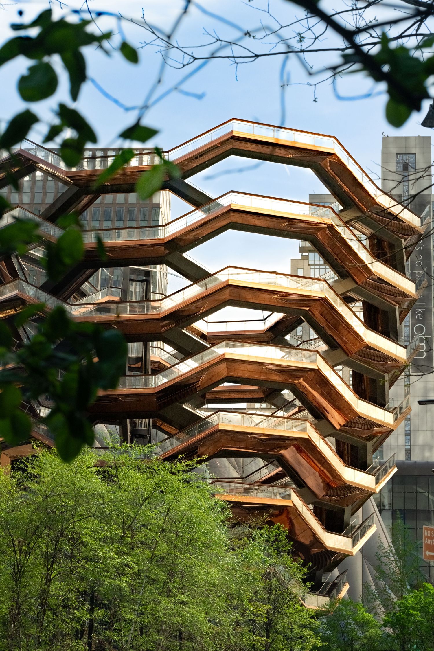 Wooden architectural structure with zigzag design among trees in urban setting.