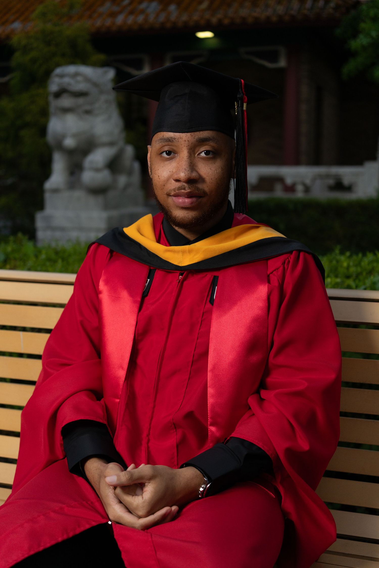 Academic regalia featuring bright red graduation robes and black mortarboard cap.