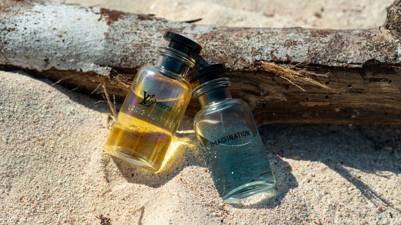Glass bottles arranged artistically on weathered driftwood and sand.