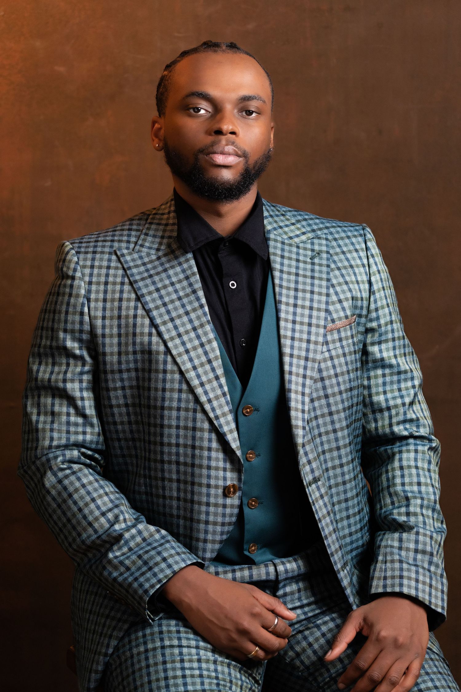 Studio portraits showcasing a checkered grey suit with vest against warm brown background.