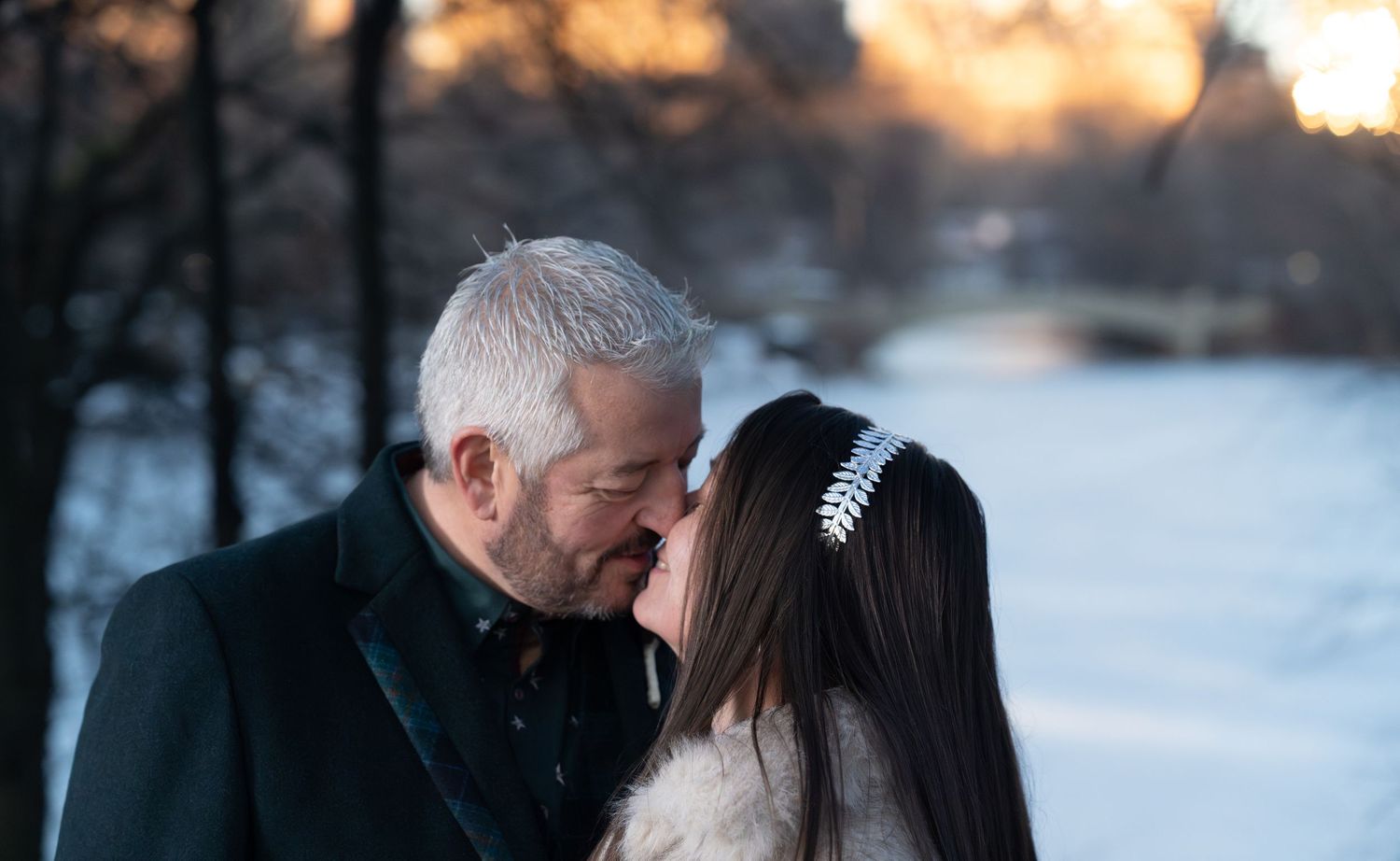 Romantic couple shares tender moments in a snowy winter setting during golden hour sunset.