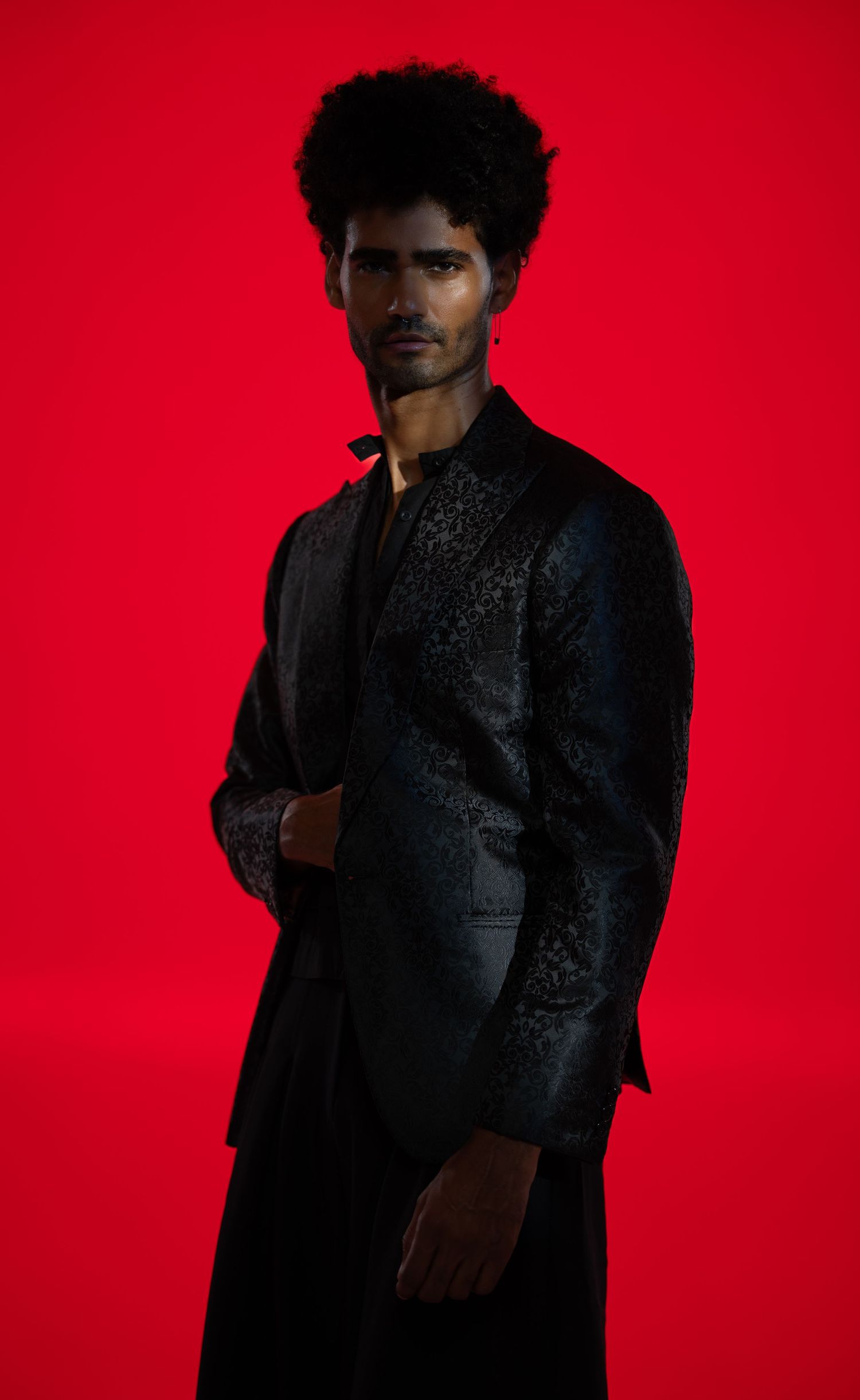 Artistic fashion portrait with figure in black against bold red backdrop.