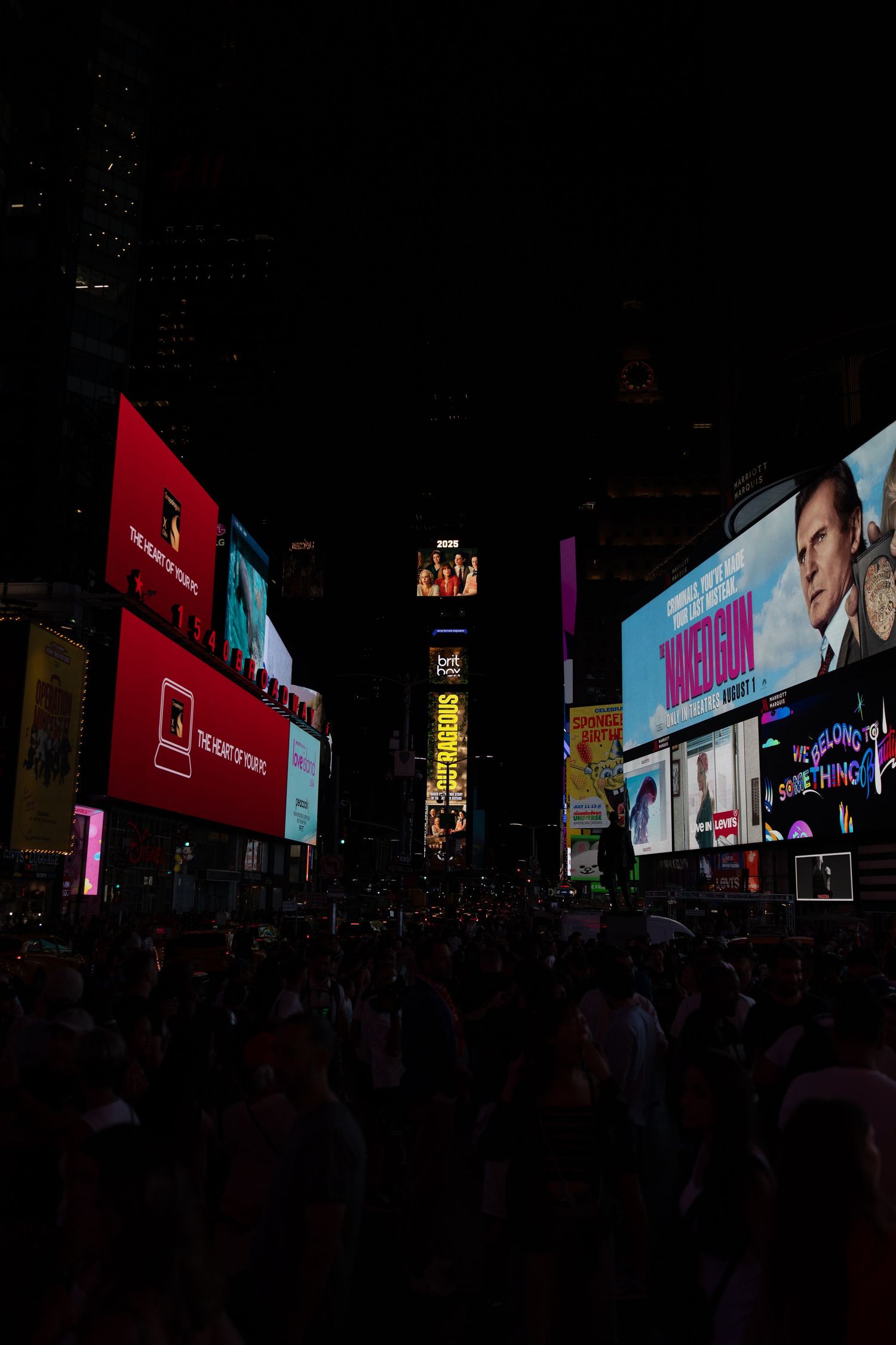 Illuminated billboards and digital displays light up Times Square at night with crowds below.
