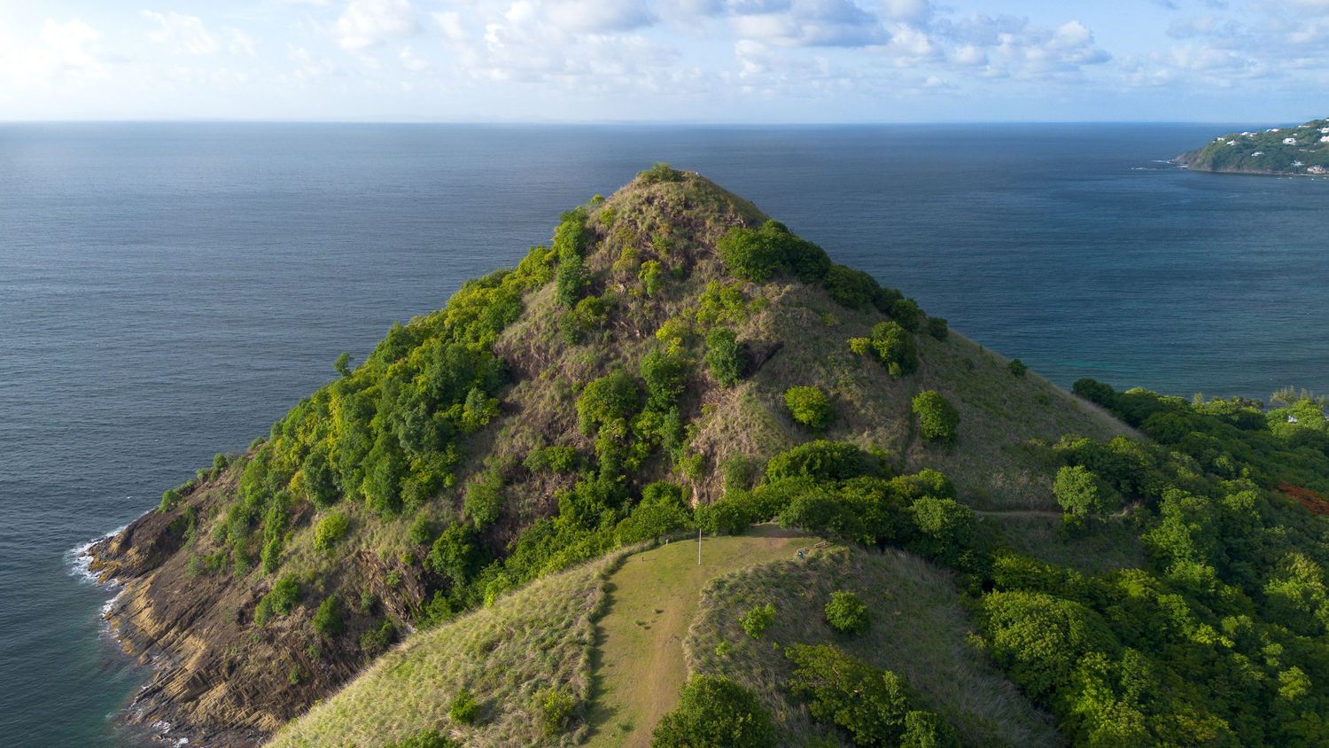 Sweeping aerial view of mountainous island terrain against a vast ocean horizon.