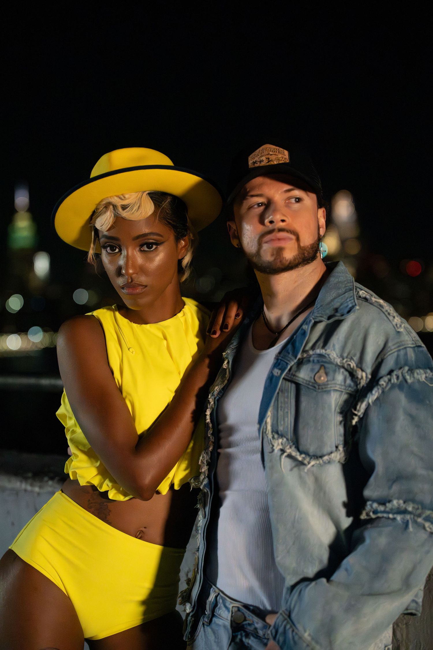 Urban fashion photography with bright yellow outfit against city lights.