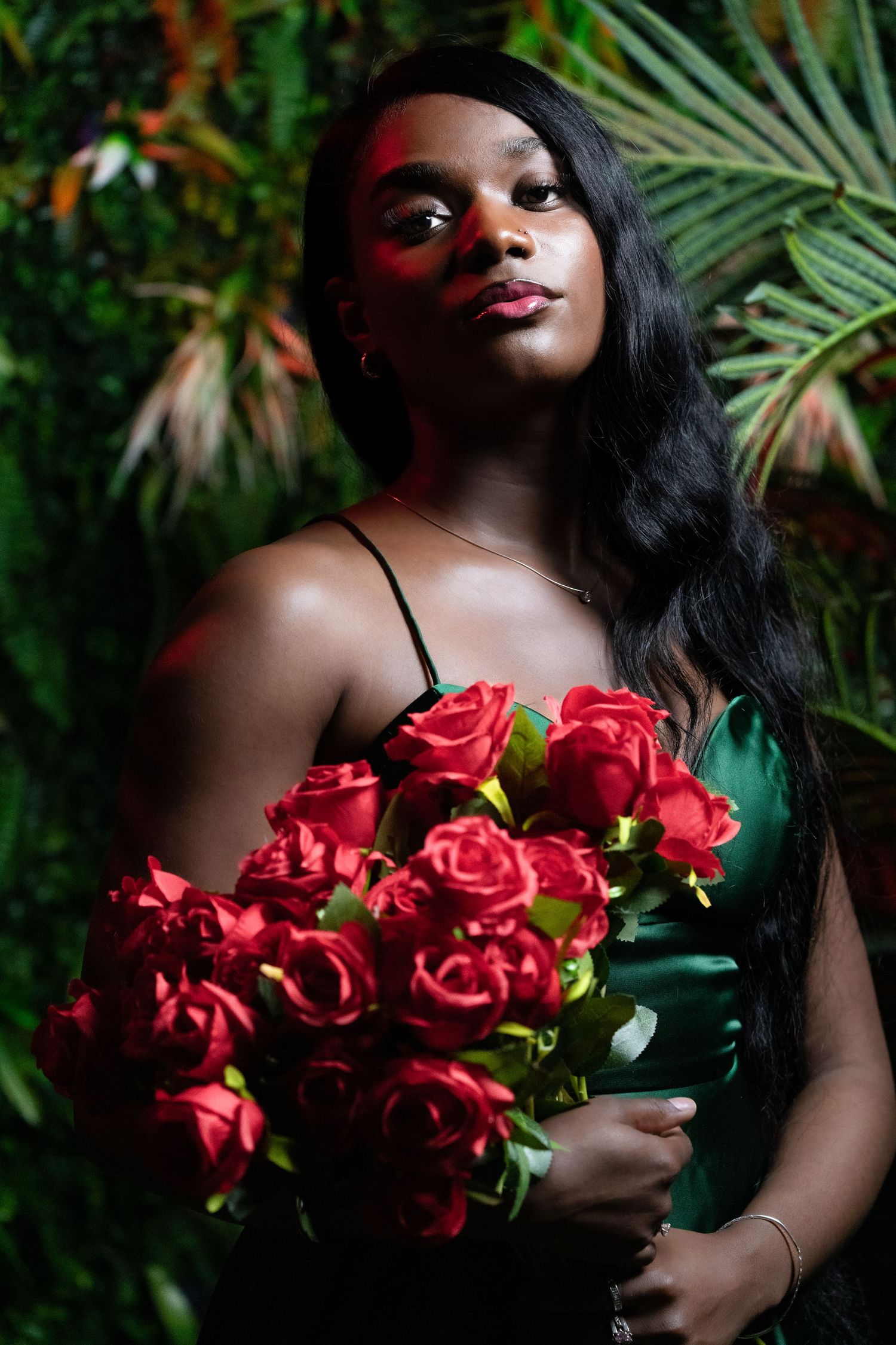 Artistic portrait with red roses against tropical foliage background.