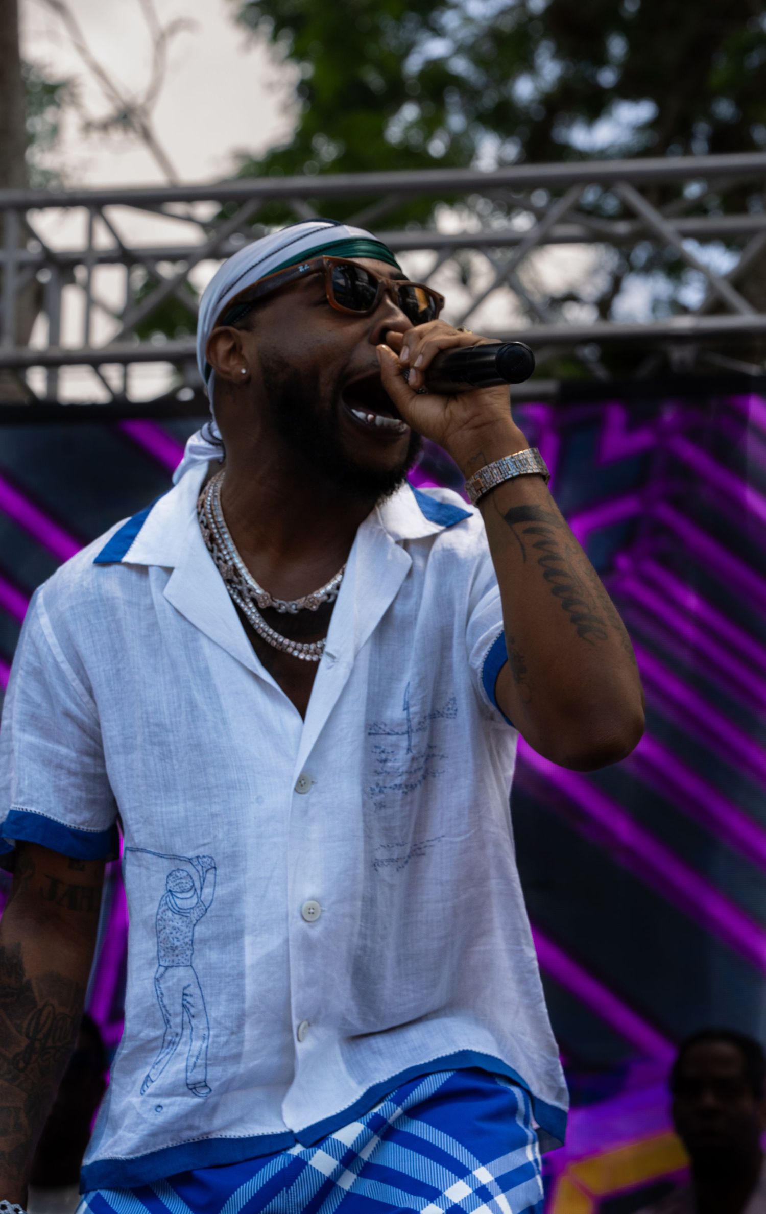 Singer in white button-down shirt performing on stage with purple lighting effects.