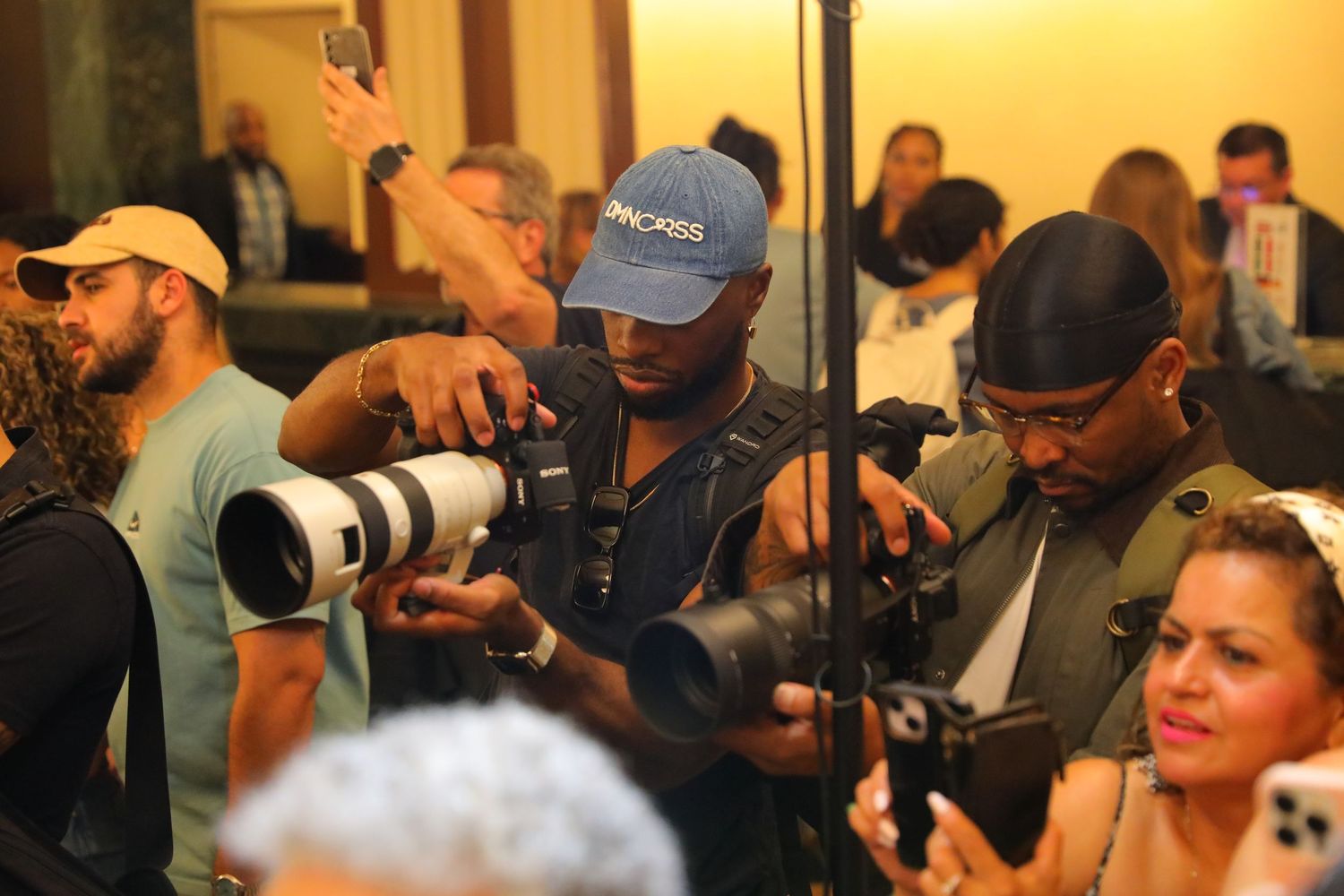Professional photographers with cameras working at a crowded event.