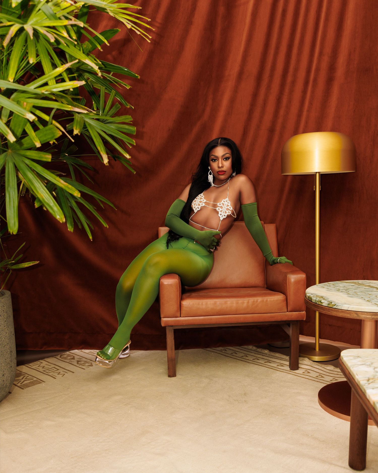 Interior photoshoot with leather chair and tropical plants against burgundy backdrop.