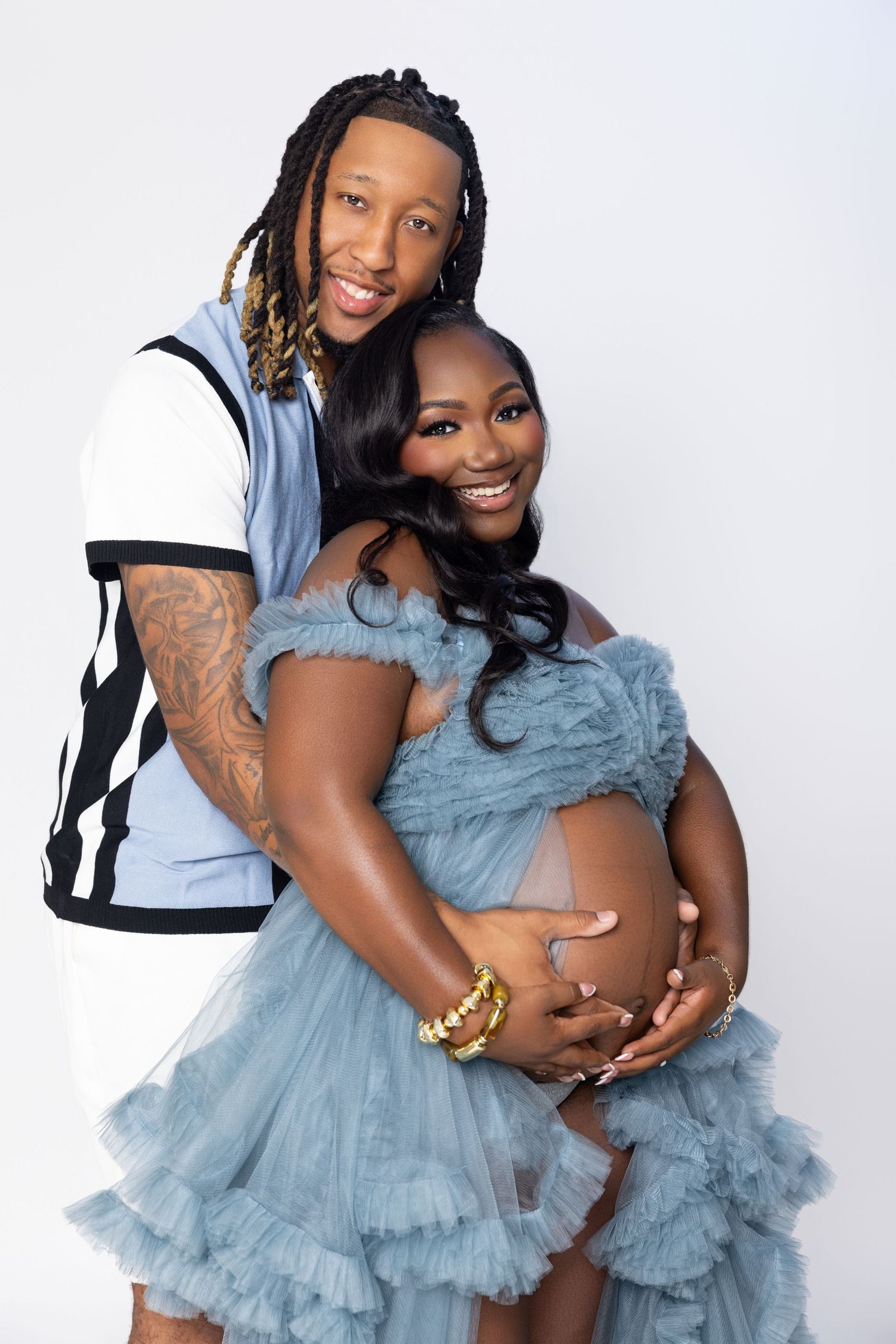 Two people in matching light blue tulle dresses embrace and smile during a photo session.