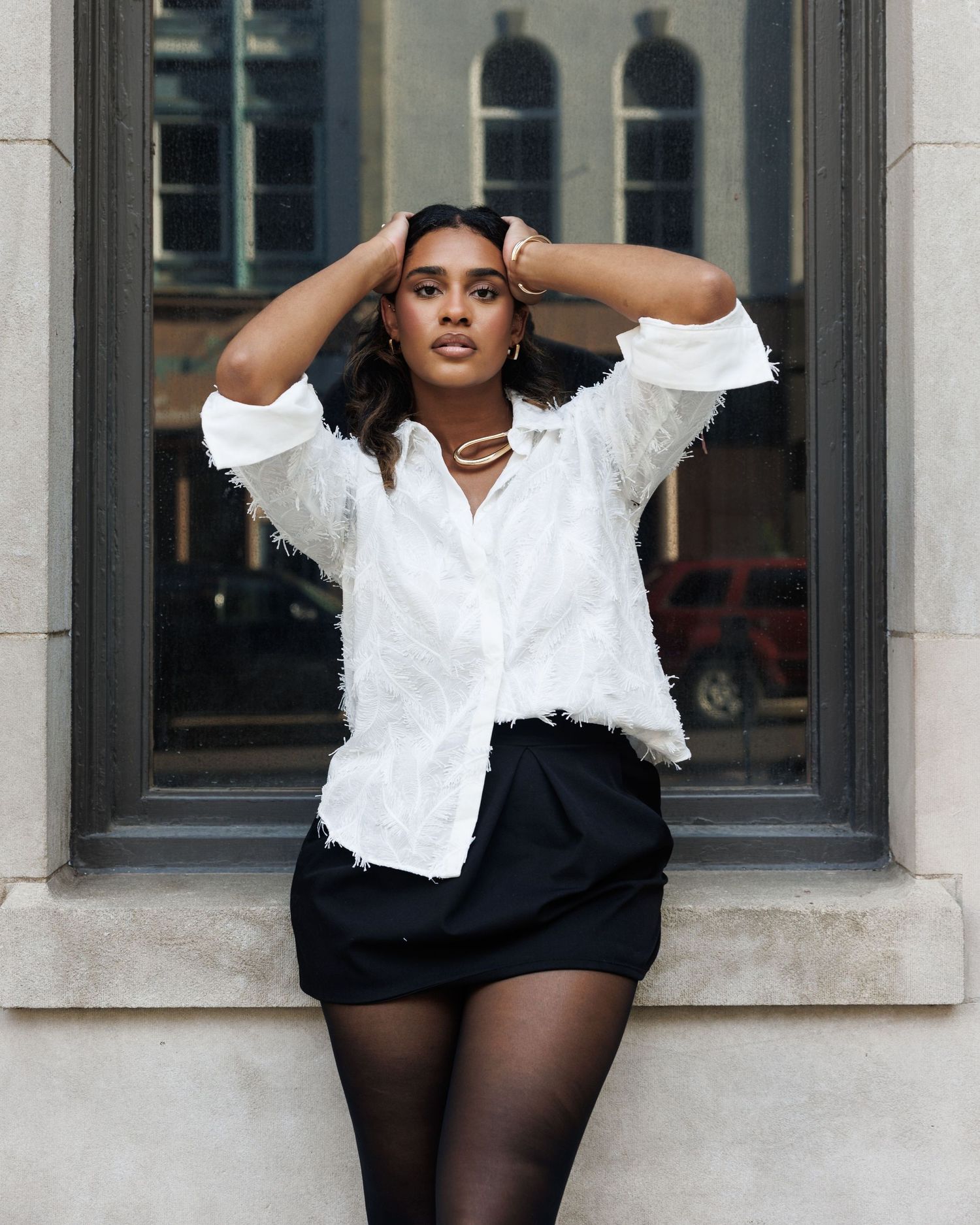 Fashion portrait in black and white featuring a white blouse, black shorts, and dramatic poses against a window backdrop.