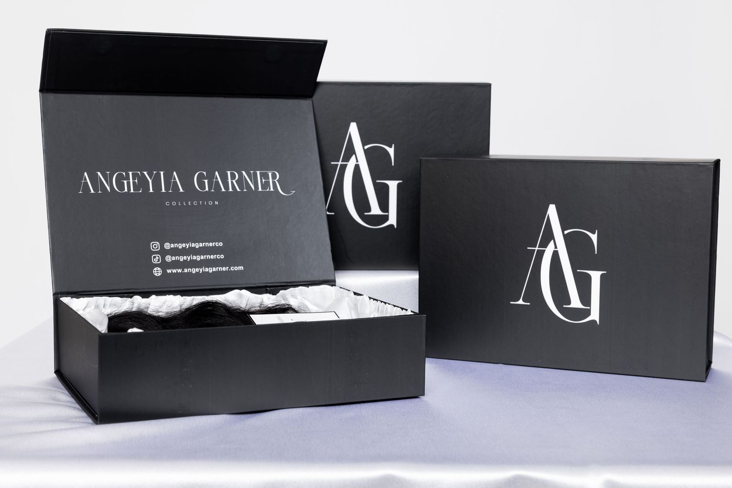 Black luxury packaging boxes with AG branding displayed against white background.