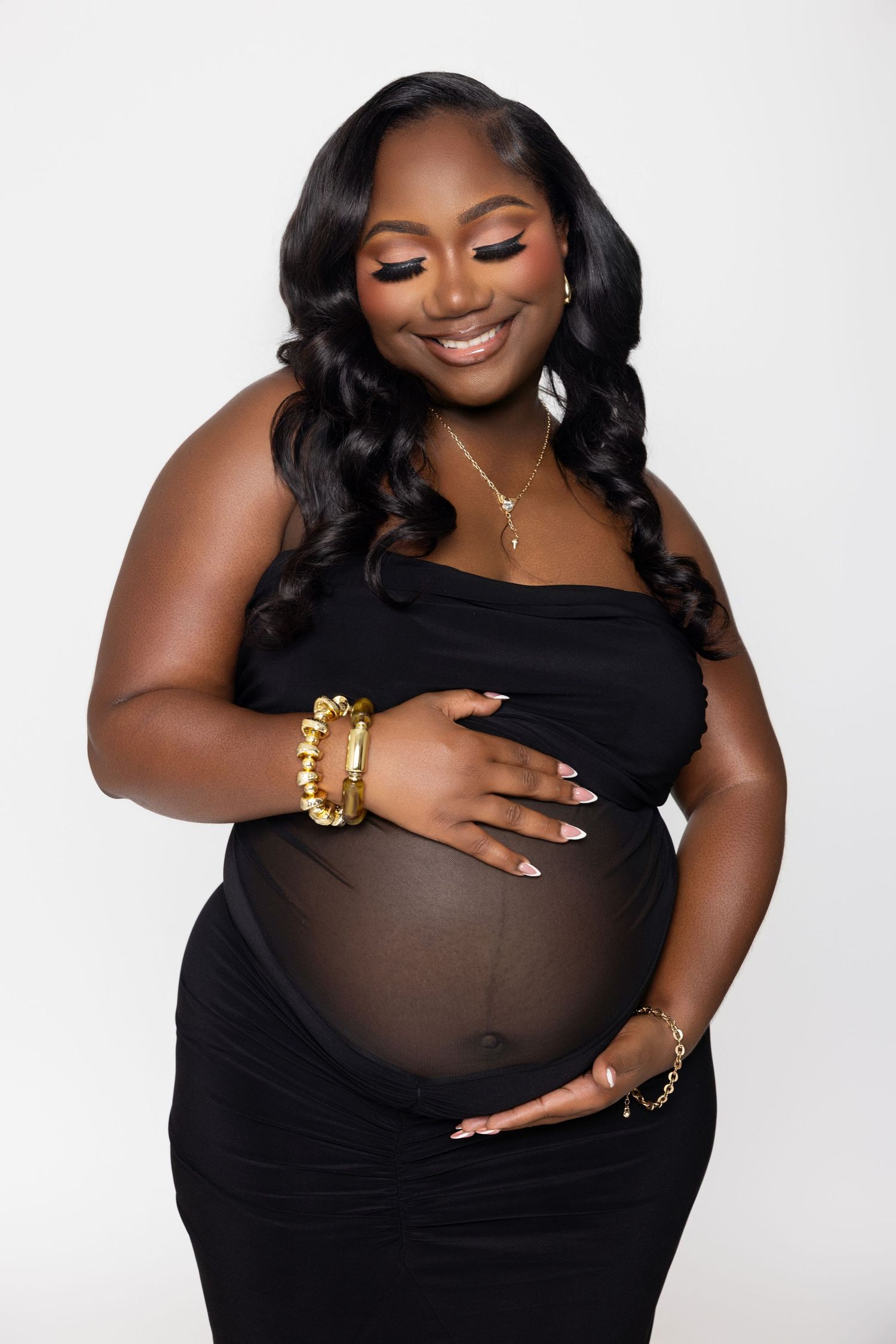 Maternity photo session featuring elegant black dress poses against white backdrop.