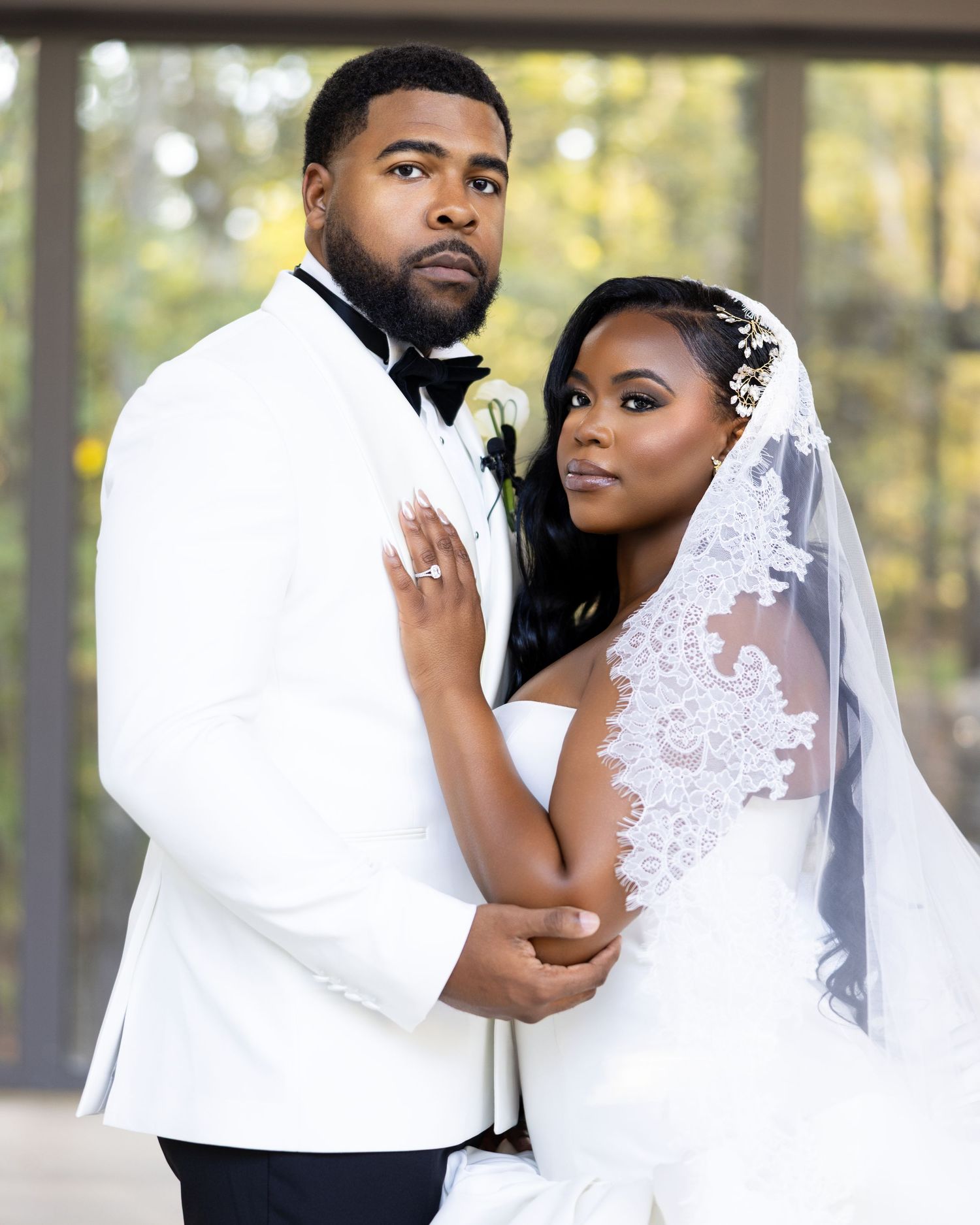 Elegant wedding portrait featuring couple in white formal attire with lace veil.