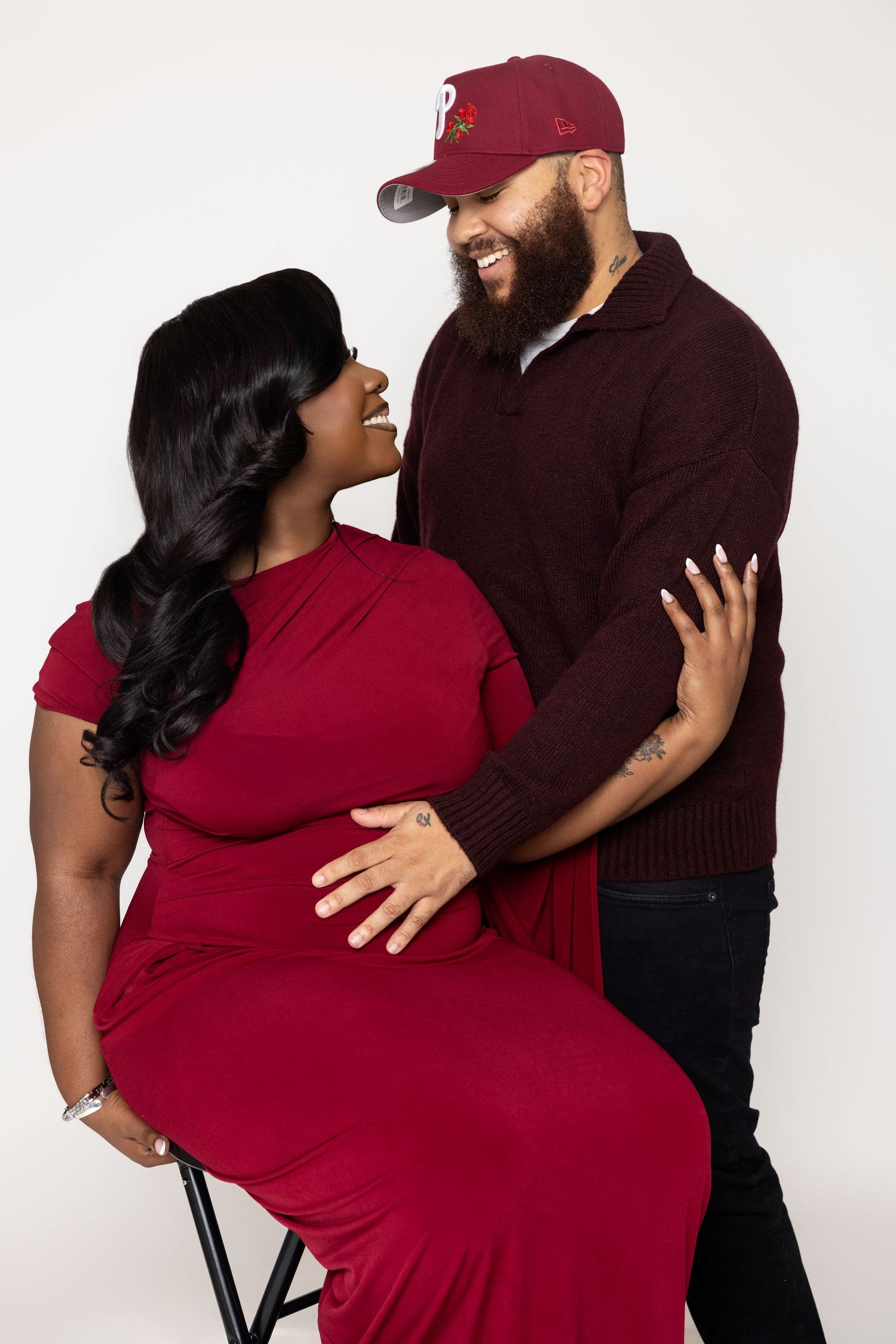 A couple in burgundy and black outfits share romantic poses in a three-photo series against a white backdrop.