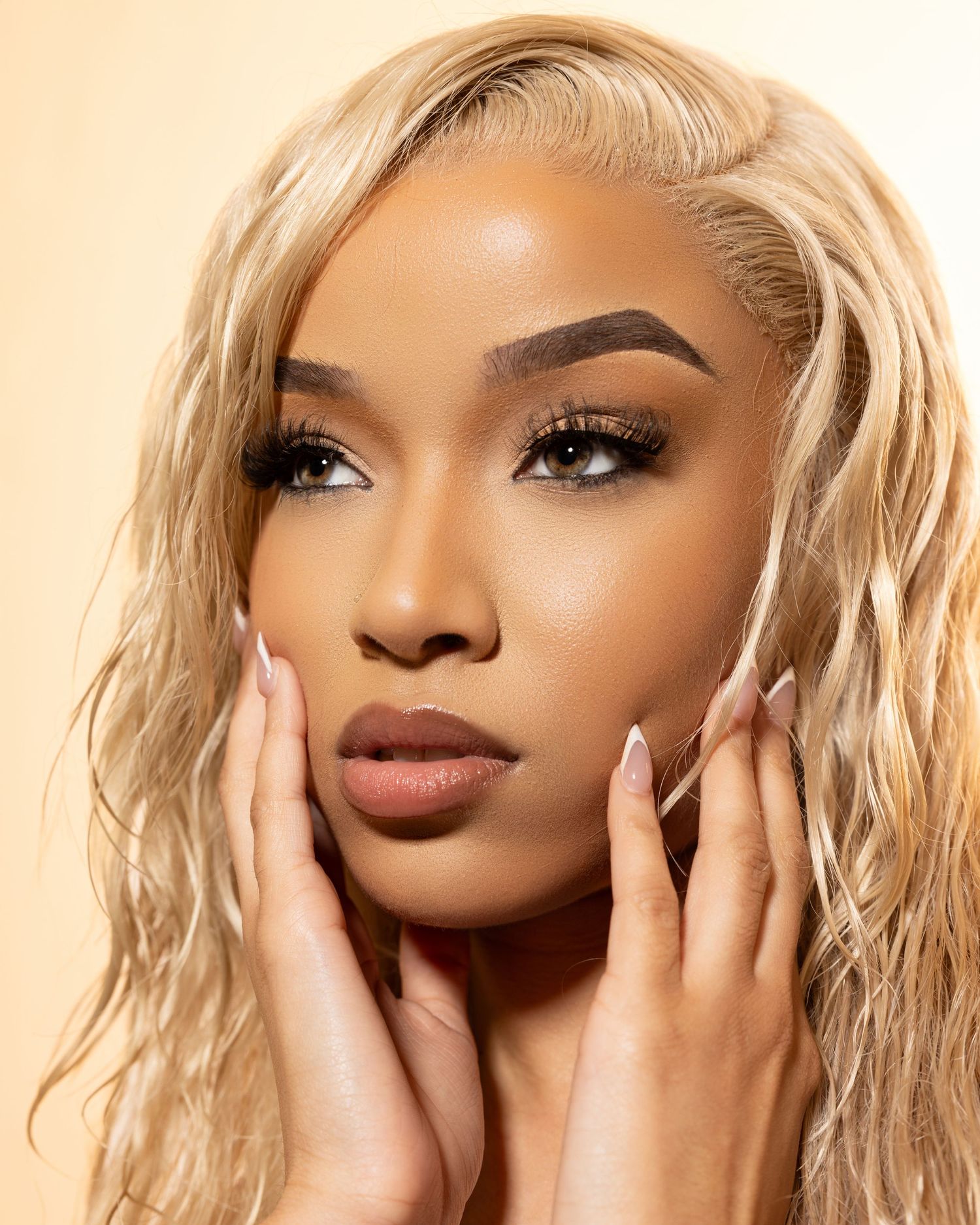 Professional beauty portraits featuring blonde hair and flawless makeup against a warm beige background.