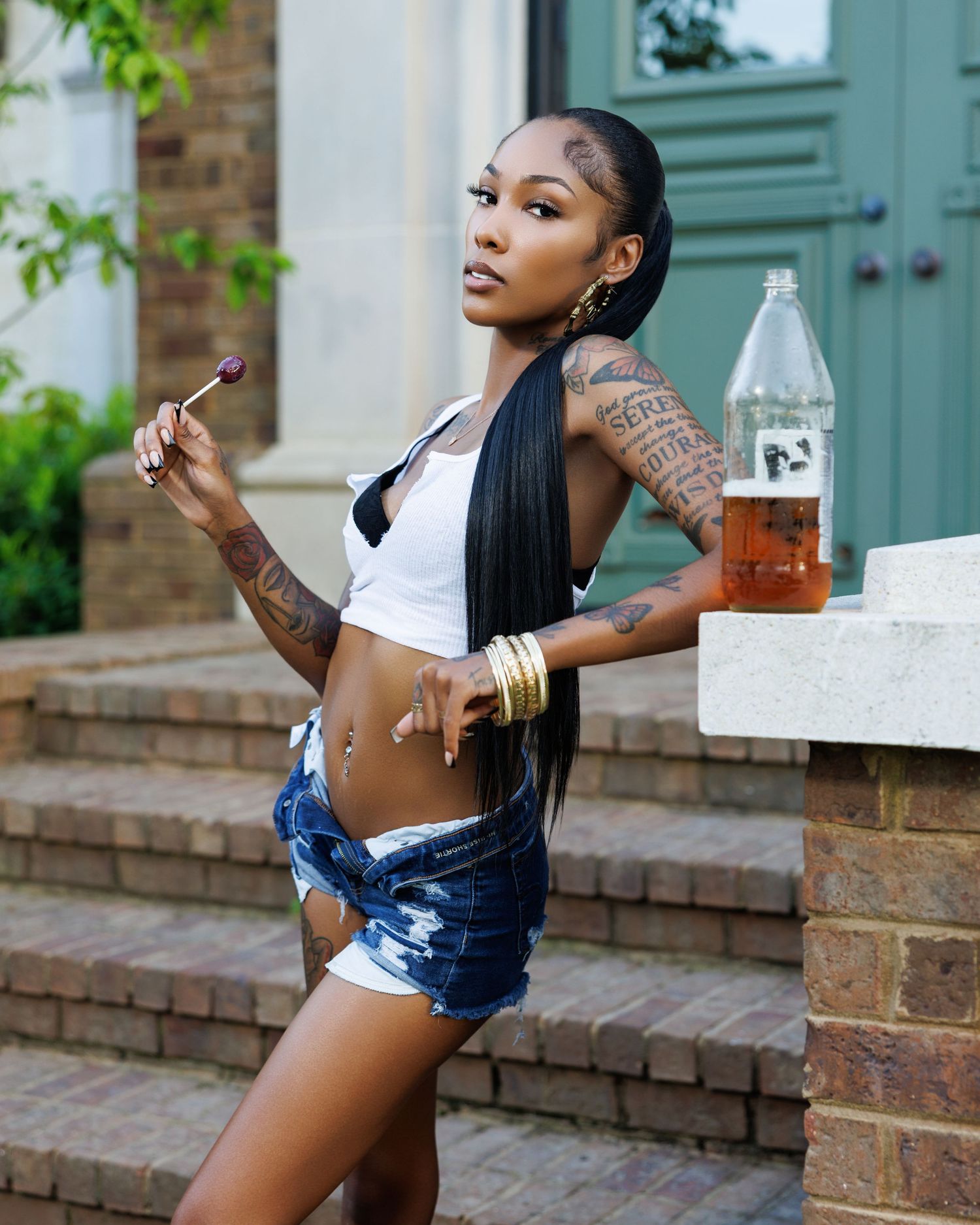 Summer fashion shoot on brick porch with denim shorts and casual styling.