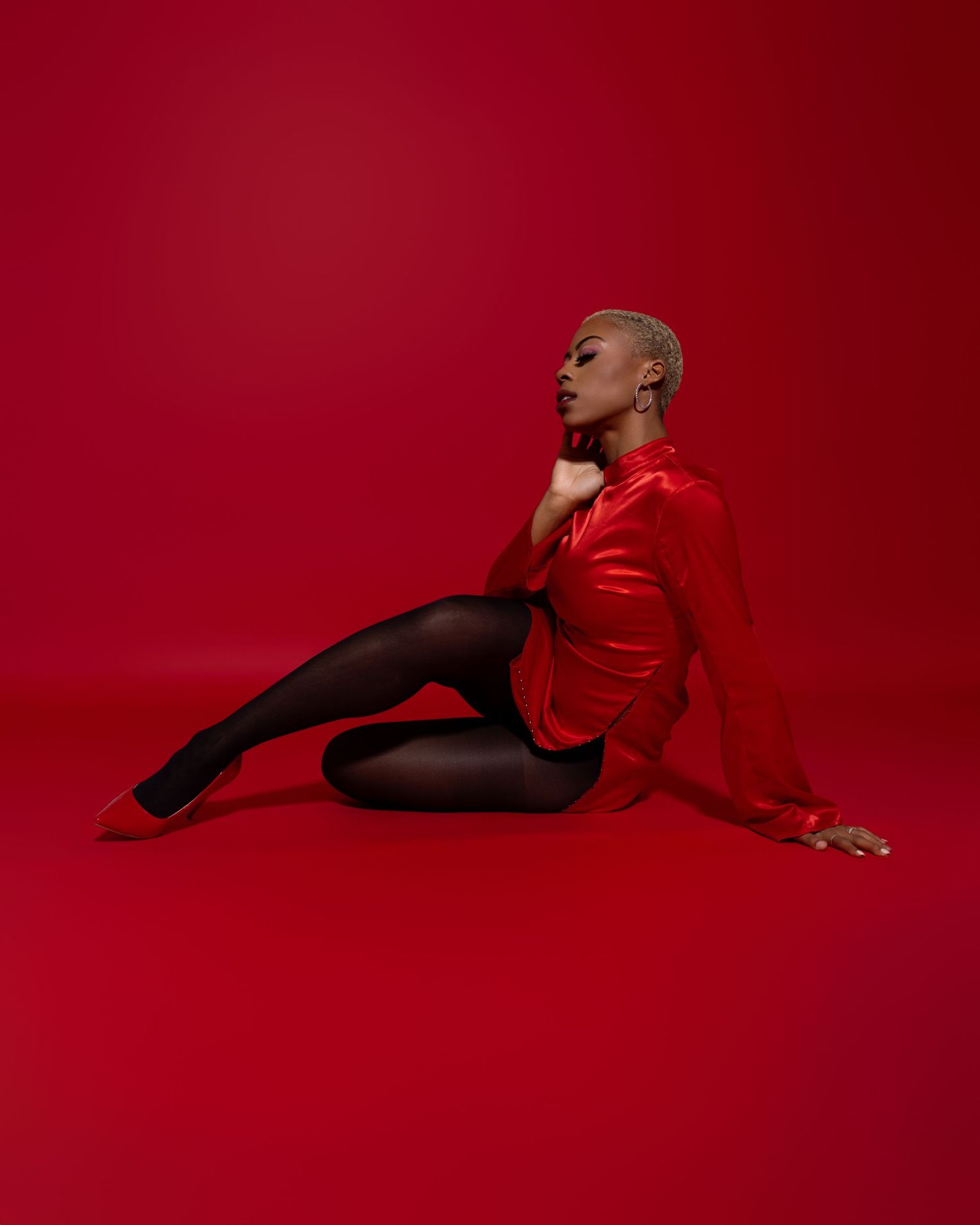 Artistic red monochrome photoshoot with dramatic poses on red backdrop.