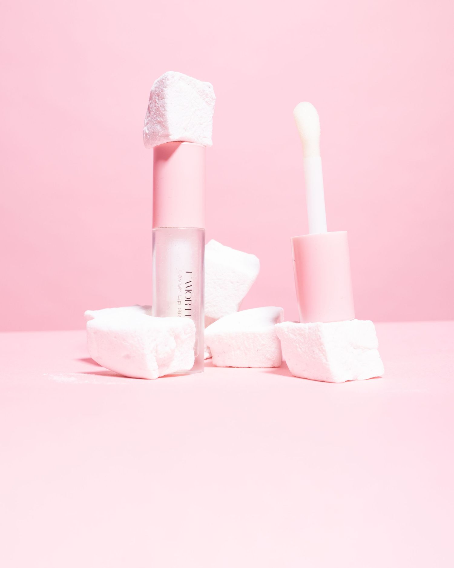 Minimalist beauty product display with pink packaging and white geometric shapes.