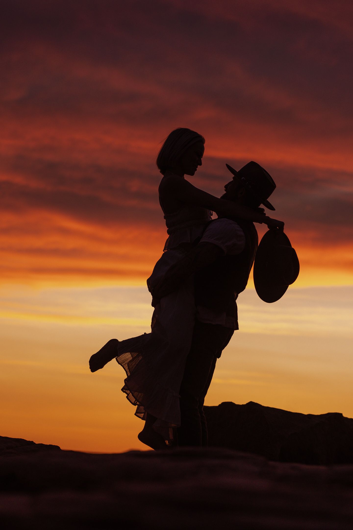 Groom lifting the bride in silhouette at a desert sunset, by Sammy Aucella Photography