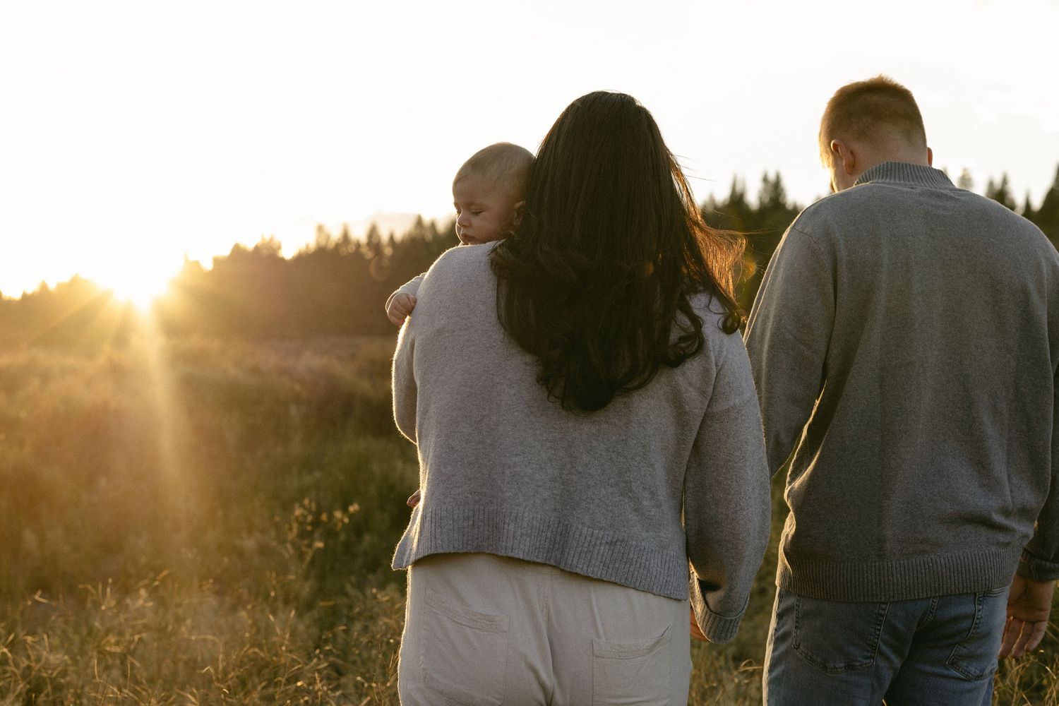 Expecting couple walking into the sunset through a golden field, tender maternity session
