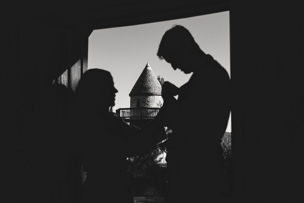 Silhouette of a couple framed by a window with the coastal inn tower beyond, dramatic Mendocino wedding photography