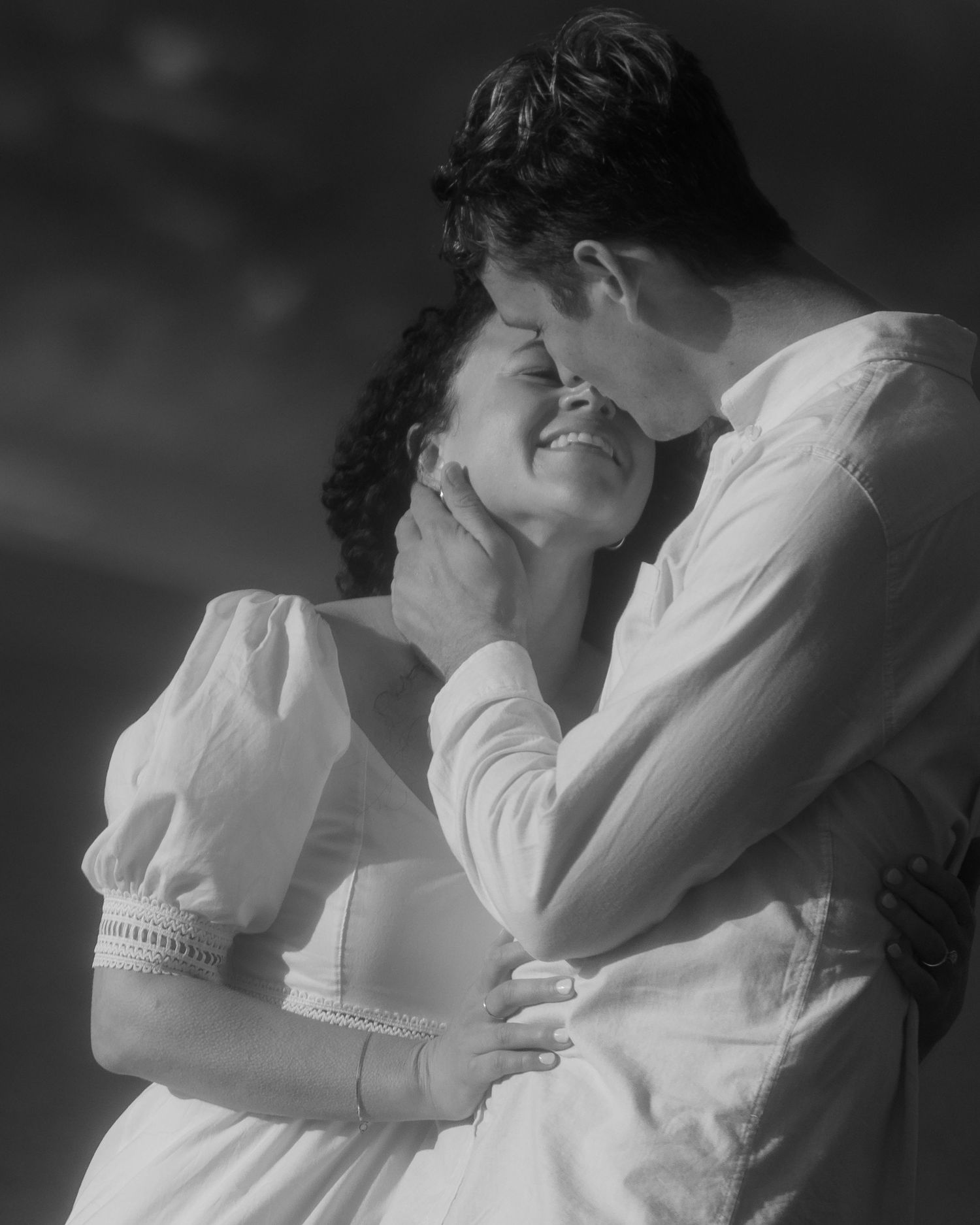 Black and white image of a couple embracing in soft light, intimate couples session
