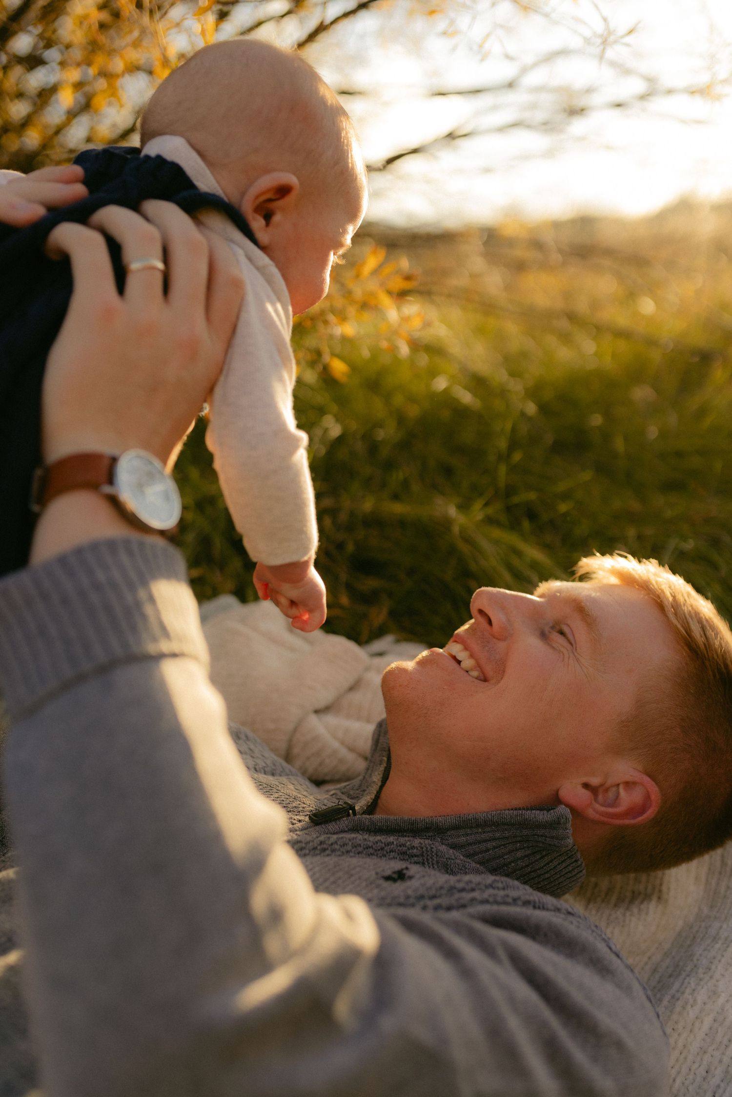 Parent lifting their baby up into the golden light, joyful candid family session