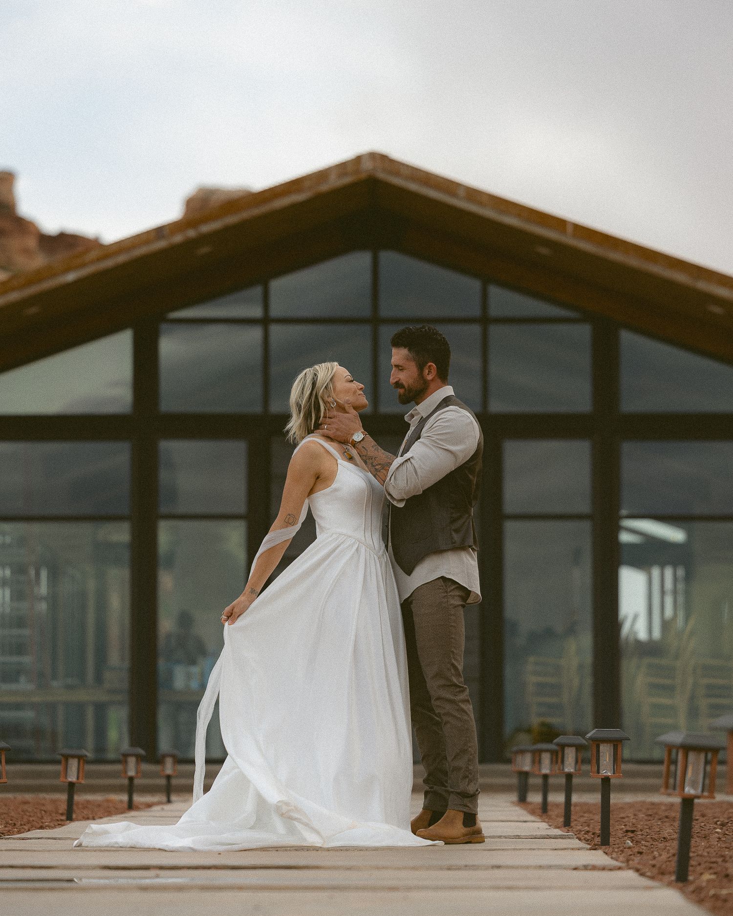 Adventurous couple embracing outside the glass A-frame at The Red Earth Venue in Moab, Utah, by Sammy Aucella Photography