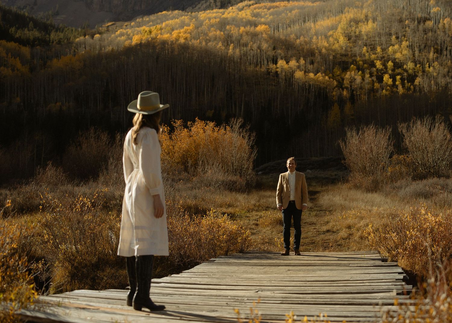 Couple on a wooden boardwalk through a golden autumn aspen meadow, Colorado mountain engagement session