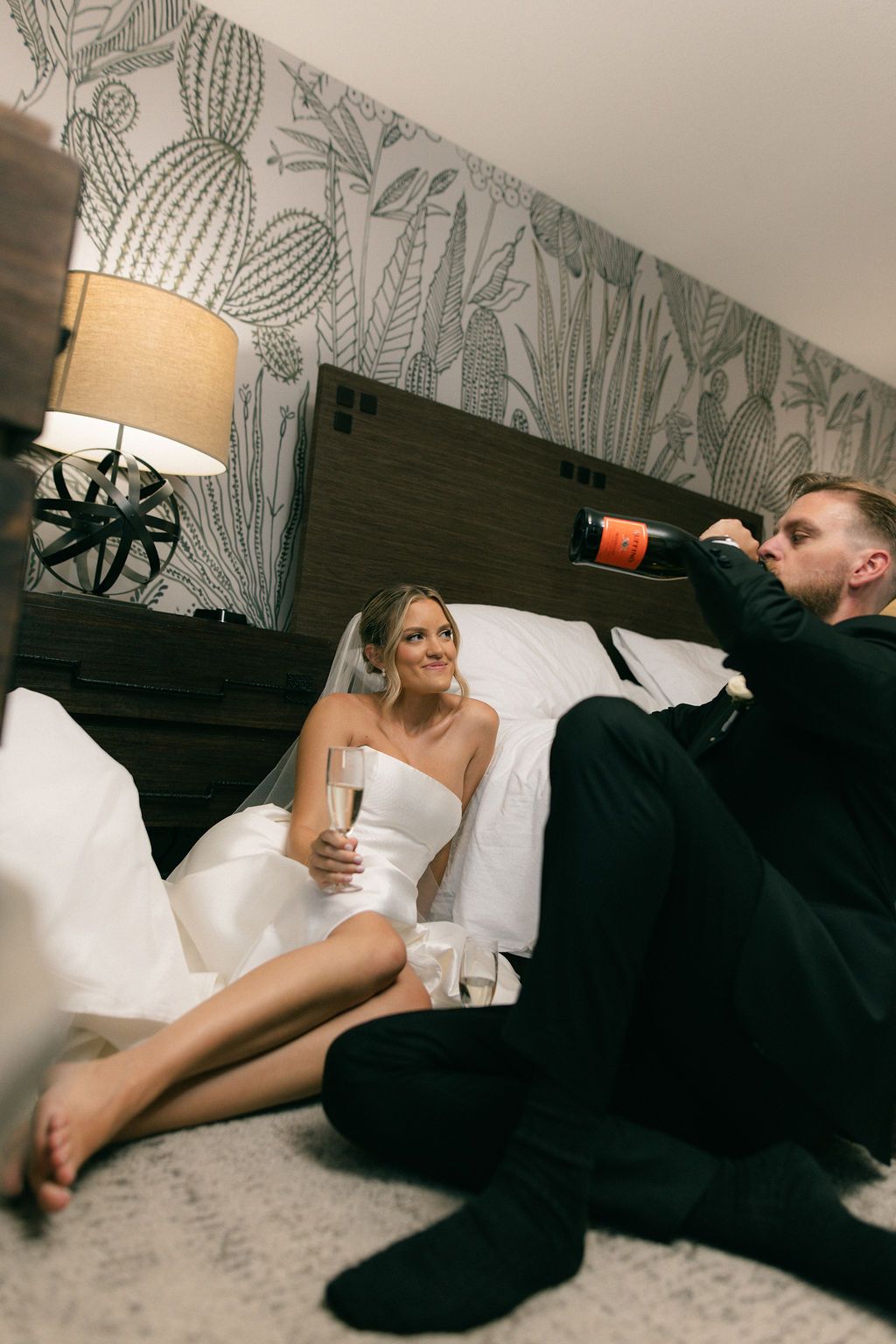 Bride and groom relaxing with champagne in a stylish hotel suite at a luxury wedding, by Sammy Aucella Photography