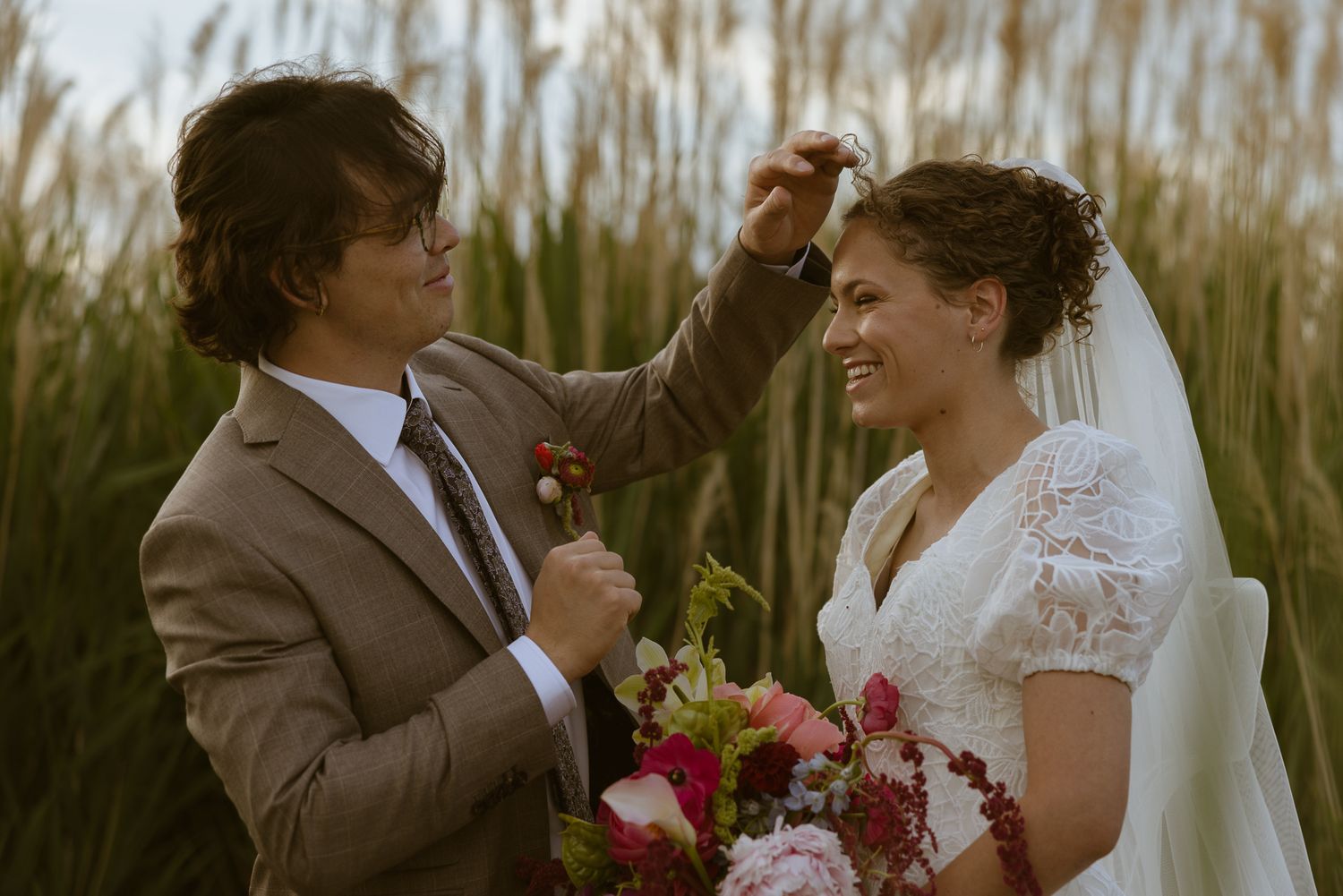 Couple sharing a candid moment in tall golden reeds, by Sammy Aucella Photography