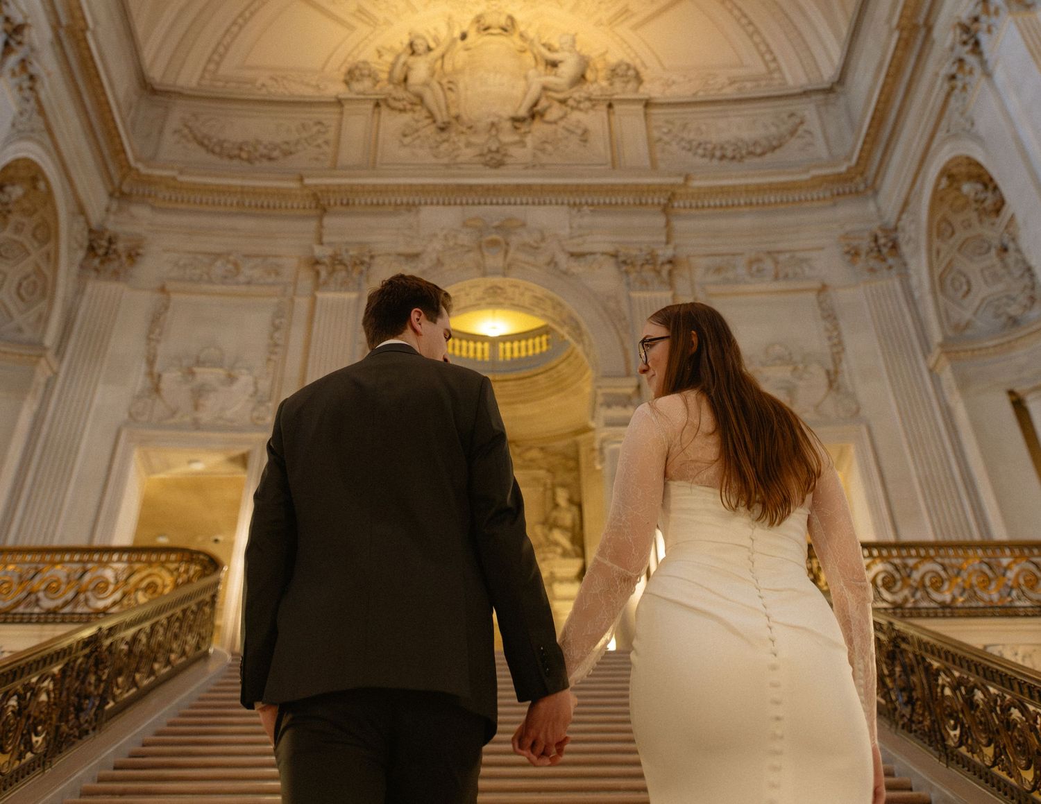 Couple descending the grand marble staircase at a San Francisco City Hall elopement, by Sammy Aucella Photography