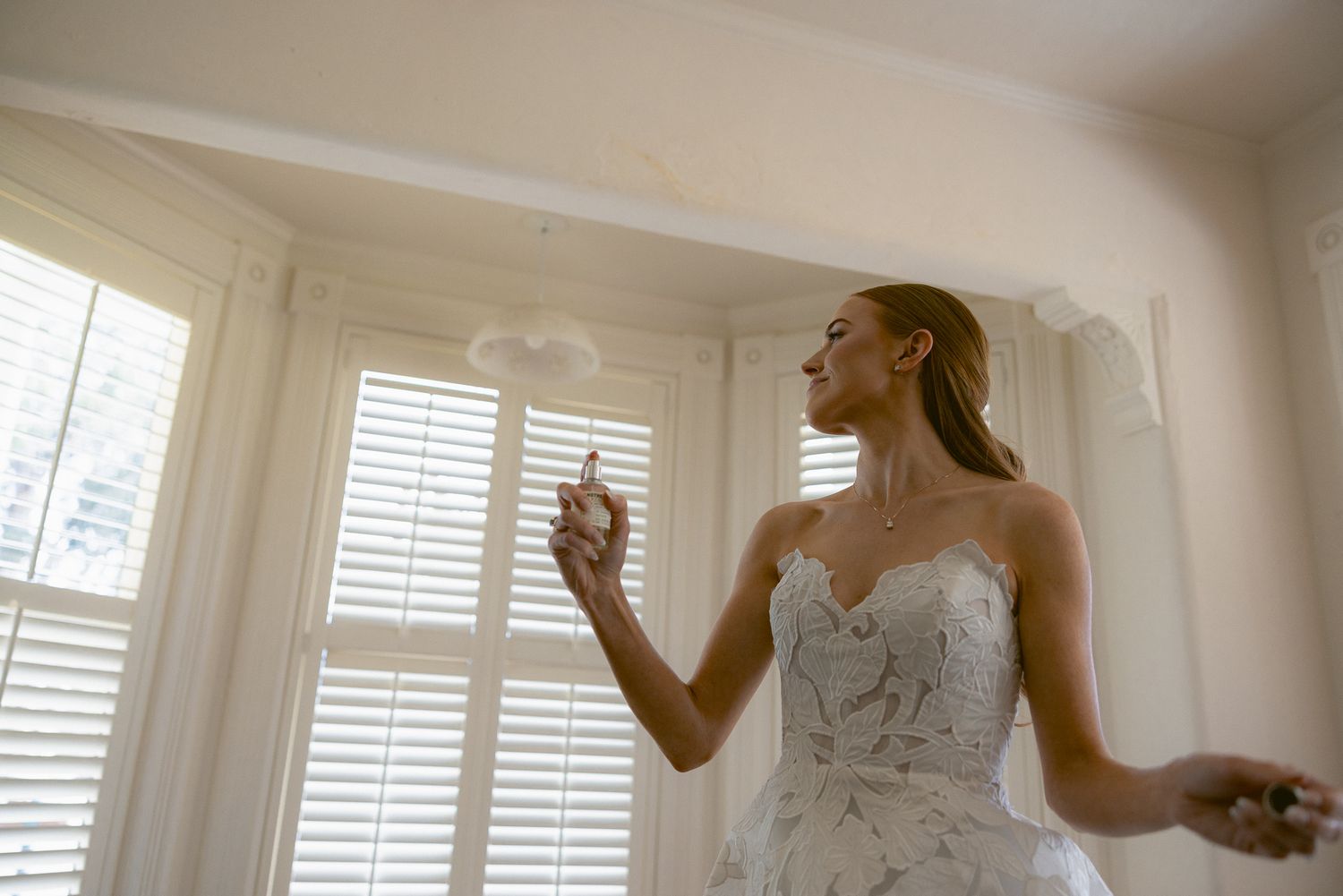 Editorial solo portrait of the bride applying perfume at a Mission Ranch wedding in Carmel, California, by Sammy Aucella Photography