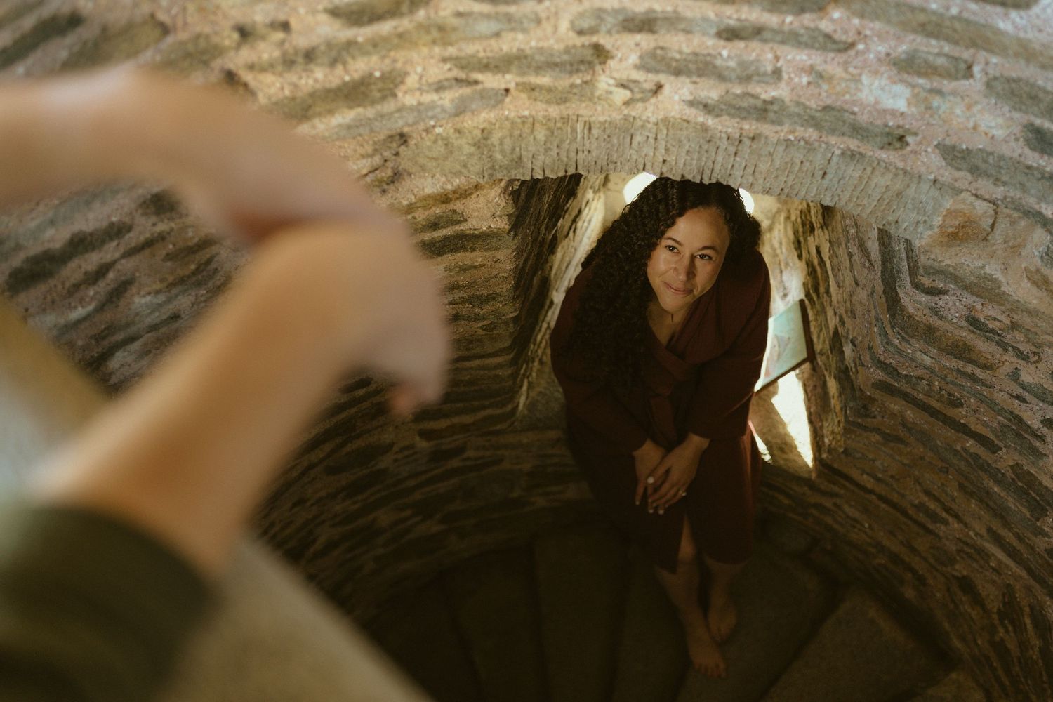 Woman in a stone archway as her veil sweeps across the frame, ethereal engagement session