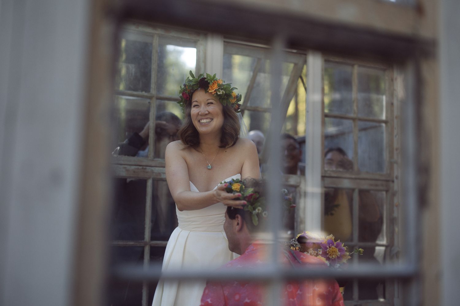 Bride in a flower crown framed in an old paned window holding her bouquet, romantic rustic wedding portrait
