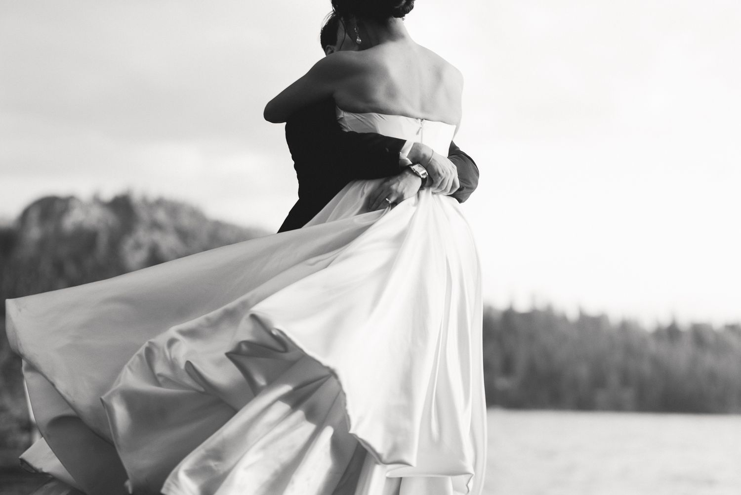 Black and white couple embracing in a flowing gown by the water at a Glenbrook wedding on Lake Tahoe, by Sammy Aucella Photography