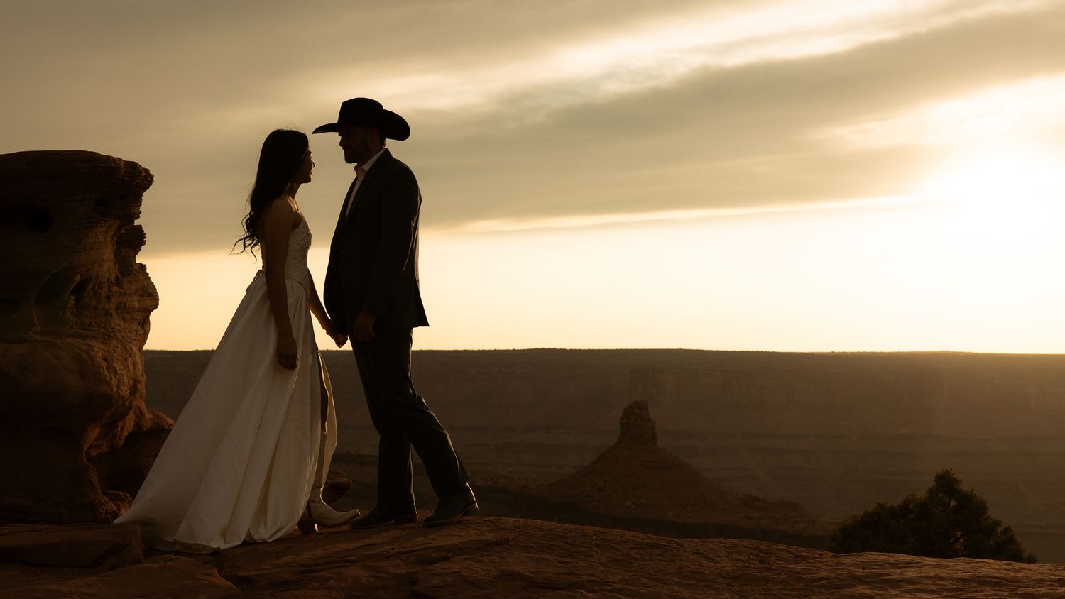 Cowboy groom and bride silhouetted at a Moab sunset in Utah, by Sammy Aucella Photography