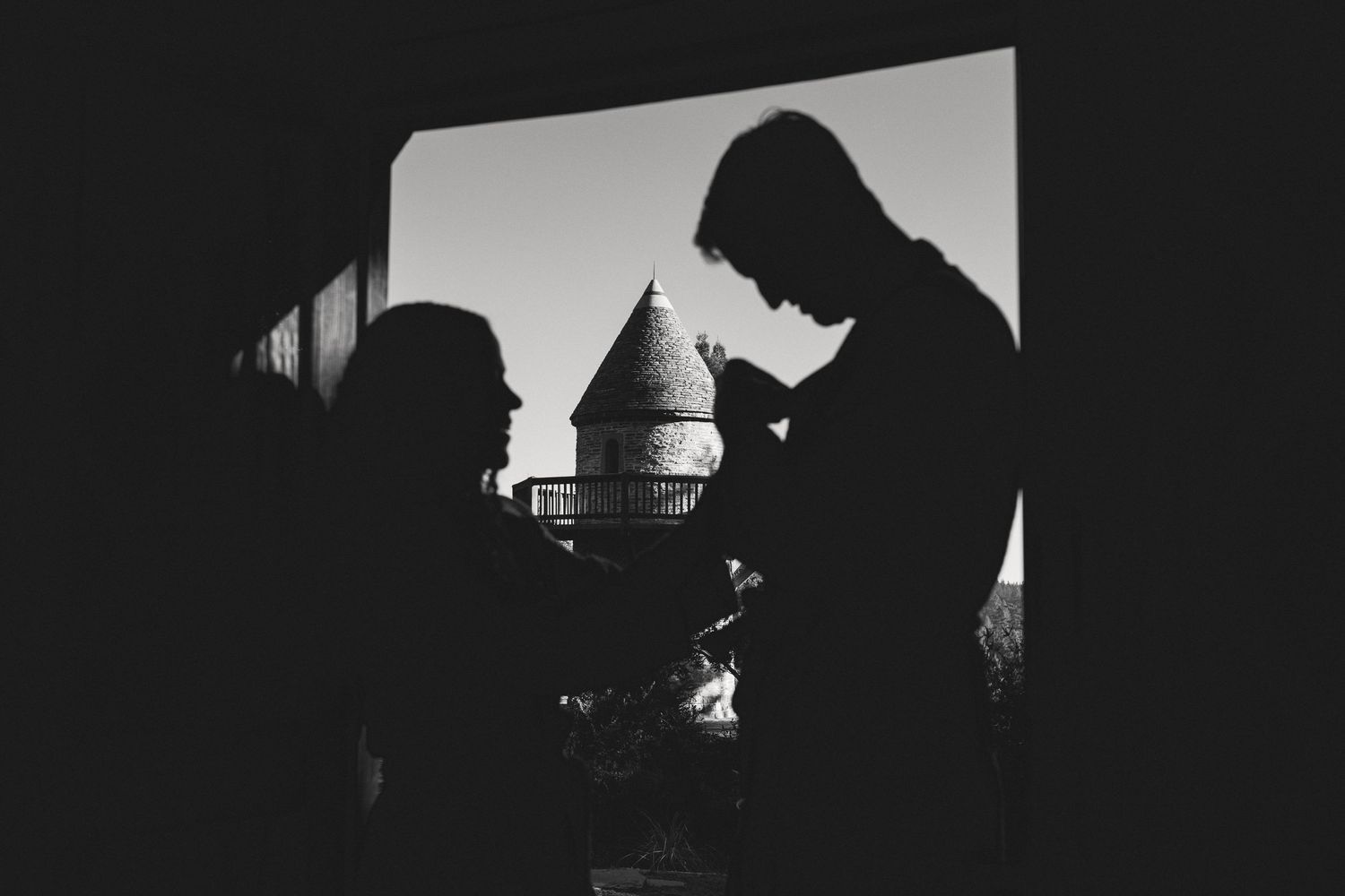 Silhouette of a couple framed by a window with the coastal inn tower beyond, dramatic Mendocino wedding photography