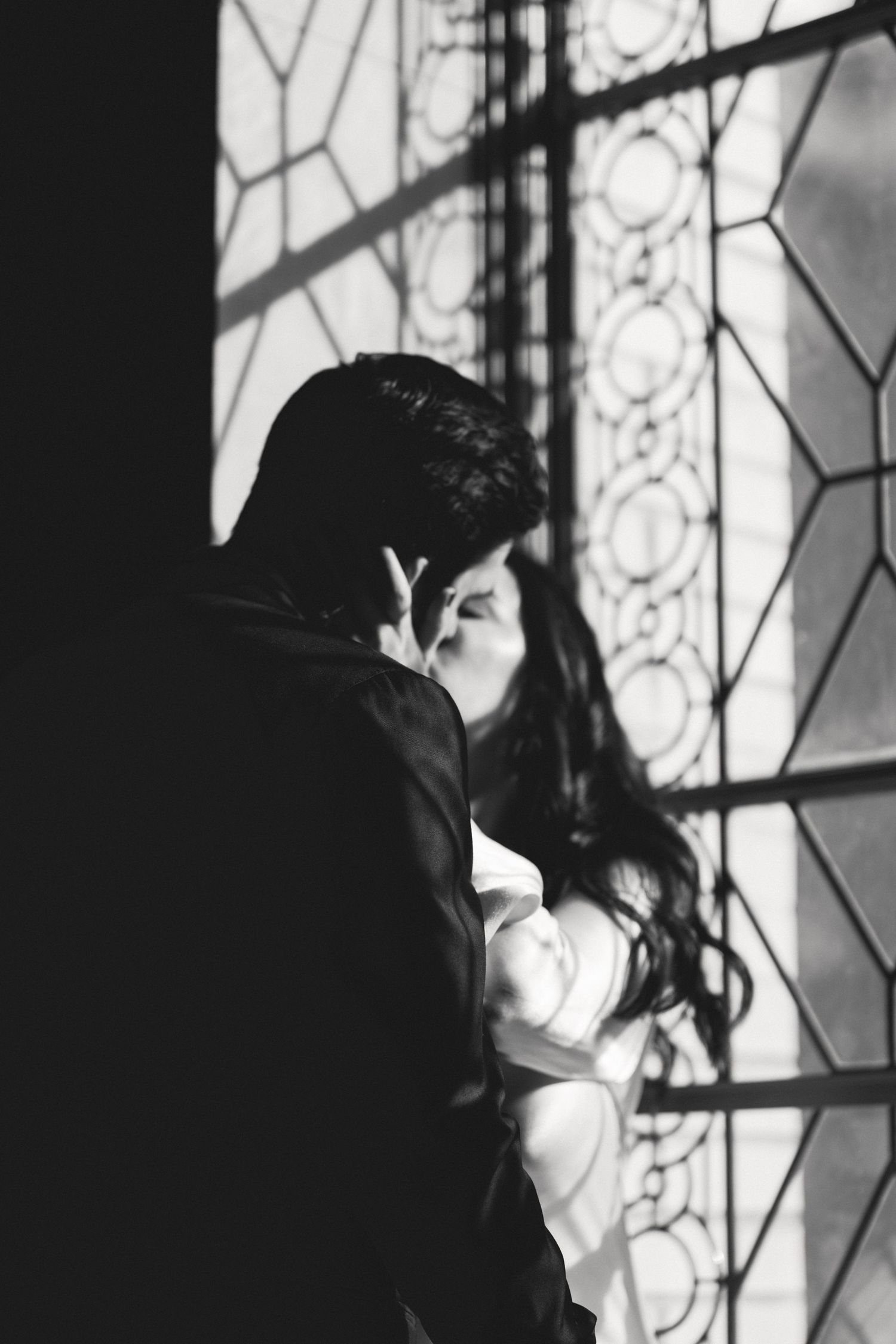 Black and white couple kissing by a patterned window at a San Francisco City Hall elopement, by Sammy Aucella Photography