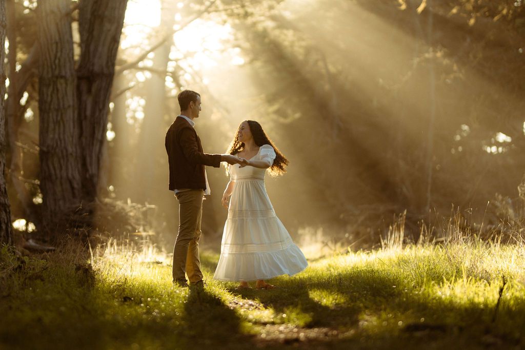 Couple dancing in a misty forest clearing as sunbeams stream through the trees, dreamy woodland elopement photography