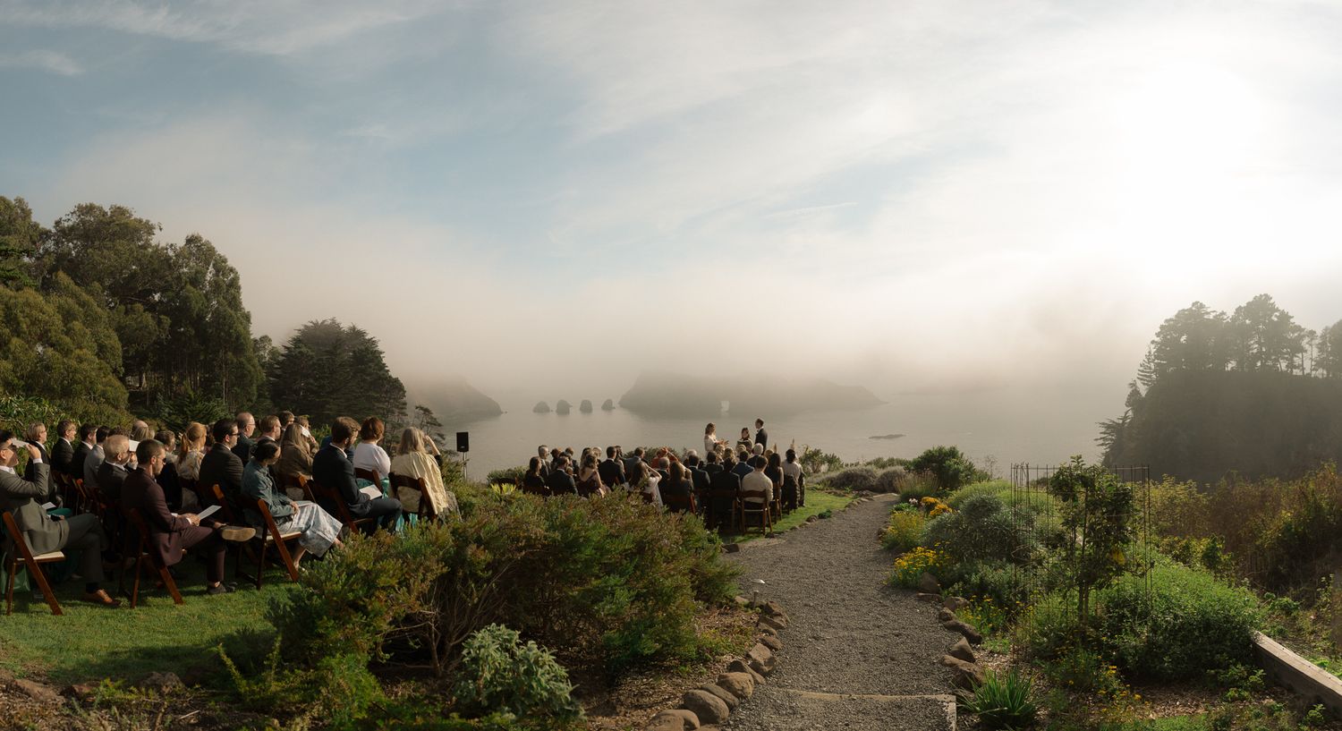 Guests seated for a coastal bluff ceremony in fog at a Harbor House Inn wedding in Mendocino, CA, by Sammy Aucella Photography