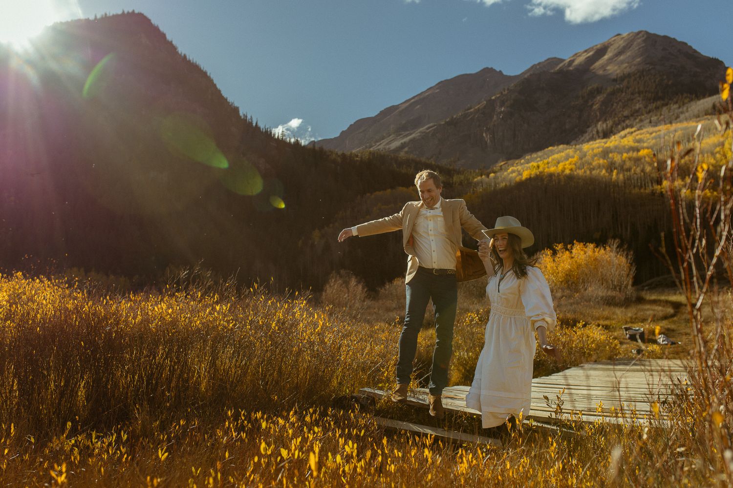 Couple in a golden mountain field with a bright sun flare, adventurous Colorado elopement photography